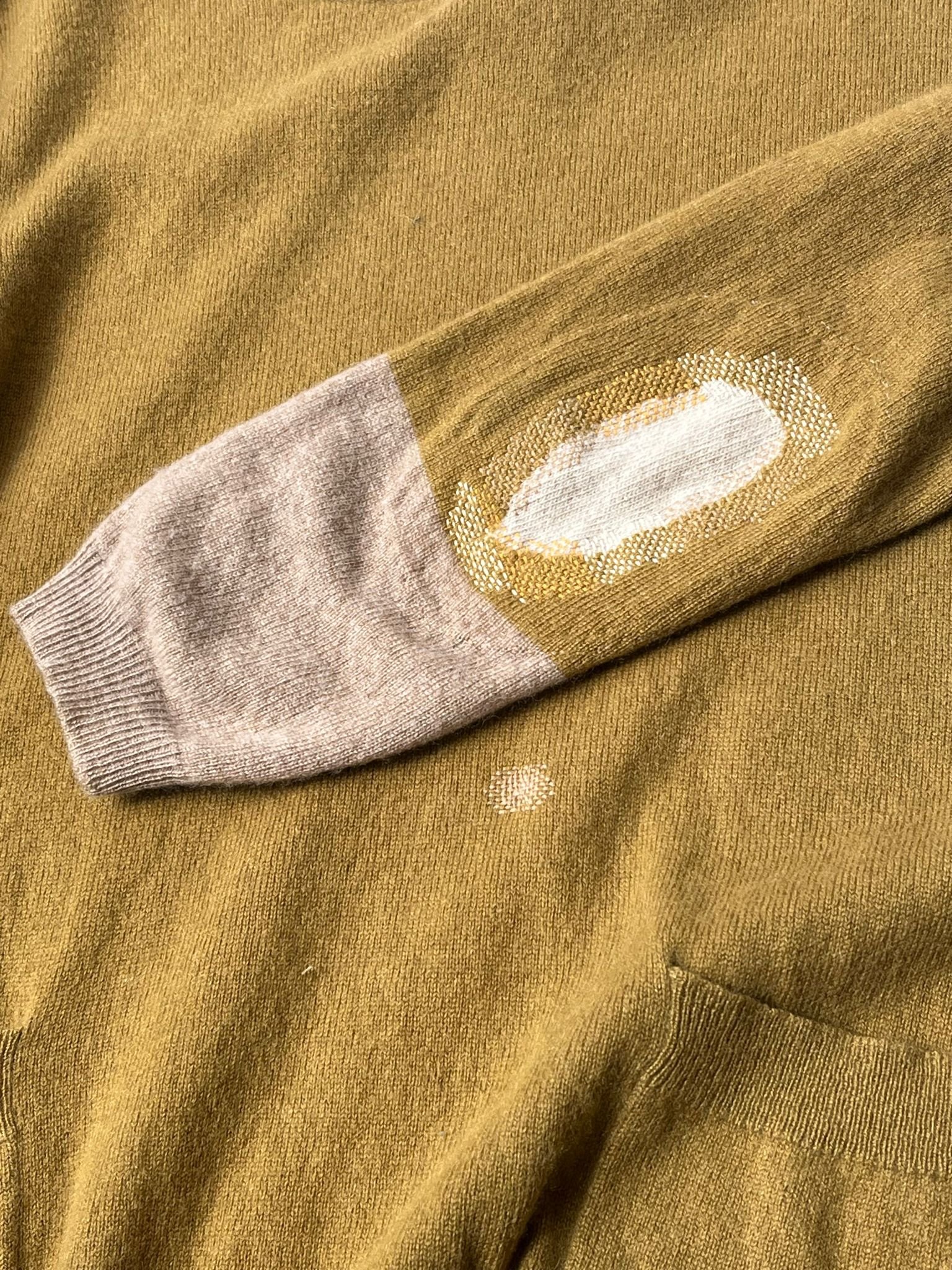 Visible mend on knitted jumper dress: Elbow hole patched with cream knitted fabric inside sleeve, stitched in place around edges with a mix of yellow threads