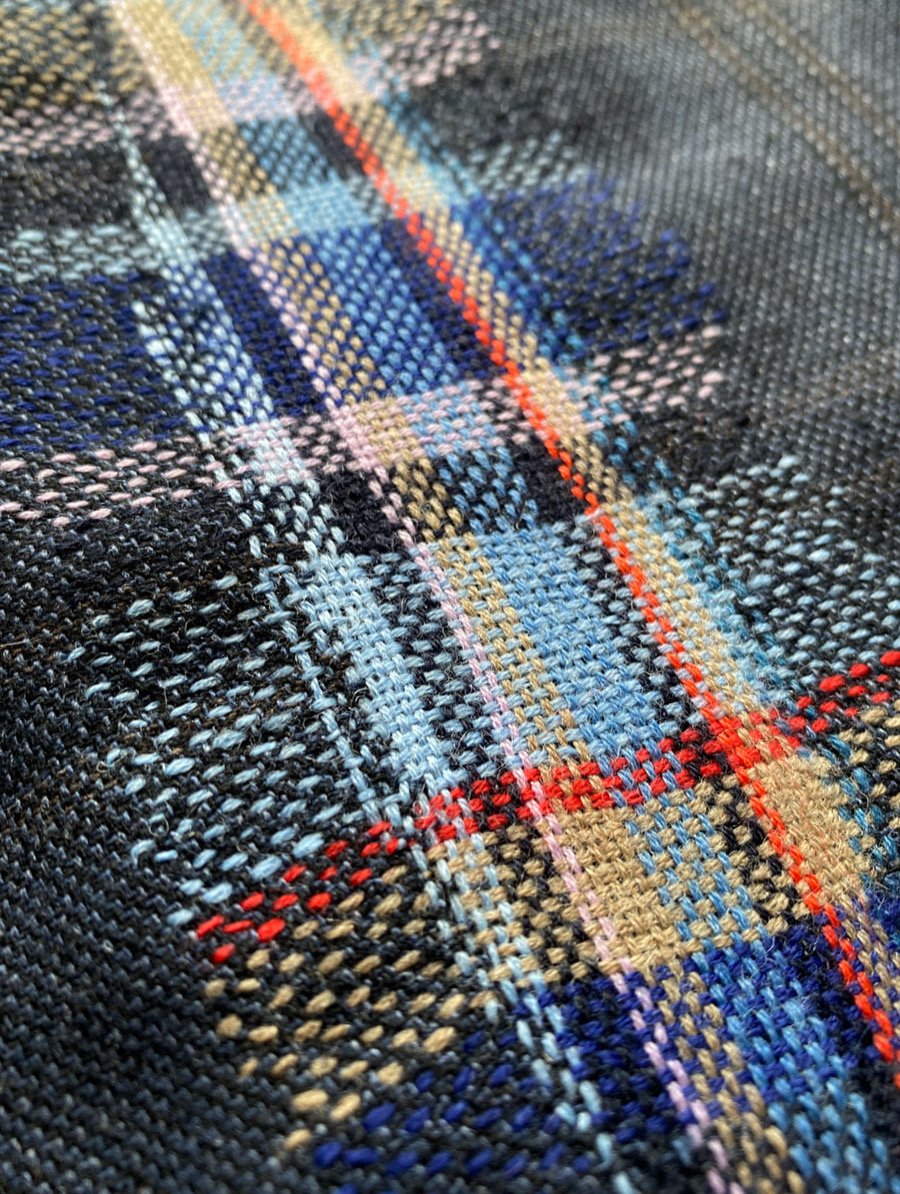 Visible darning on woven wool: Close up image of woven darn