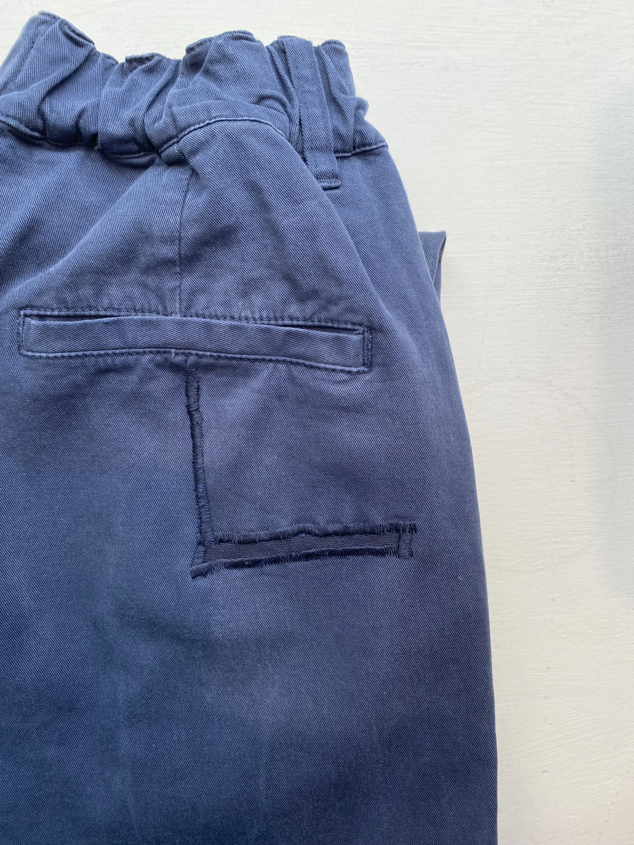 Discreet repair on navy trouser seat pocket, patched on reverse and stitch in place with sewing machine in almost matching thread and fabric