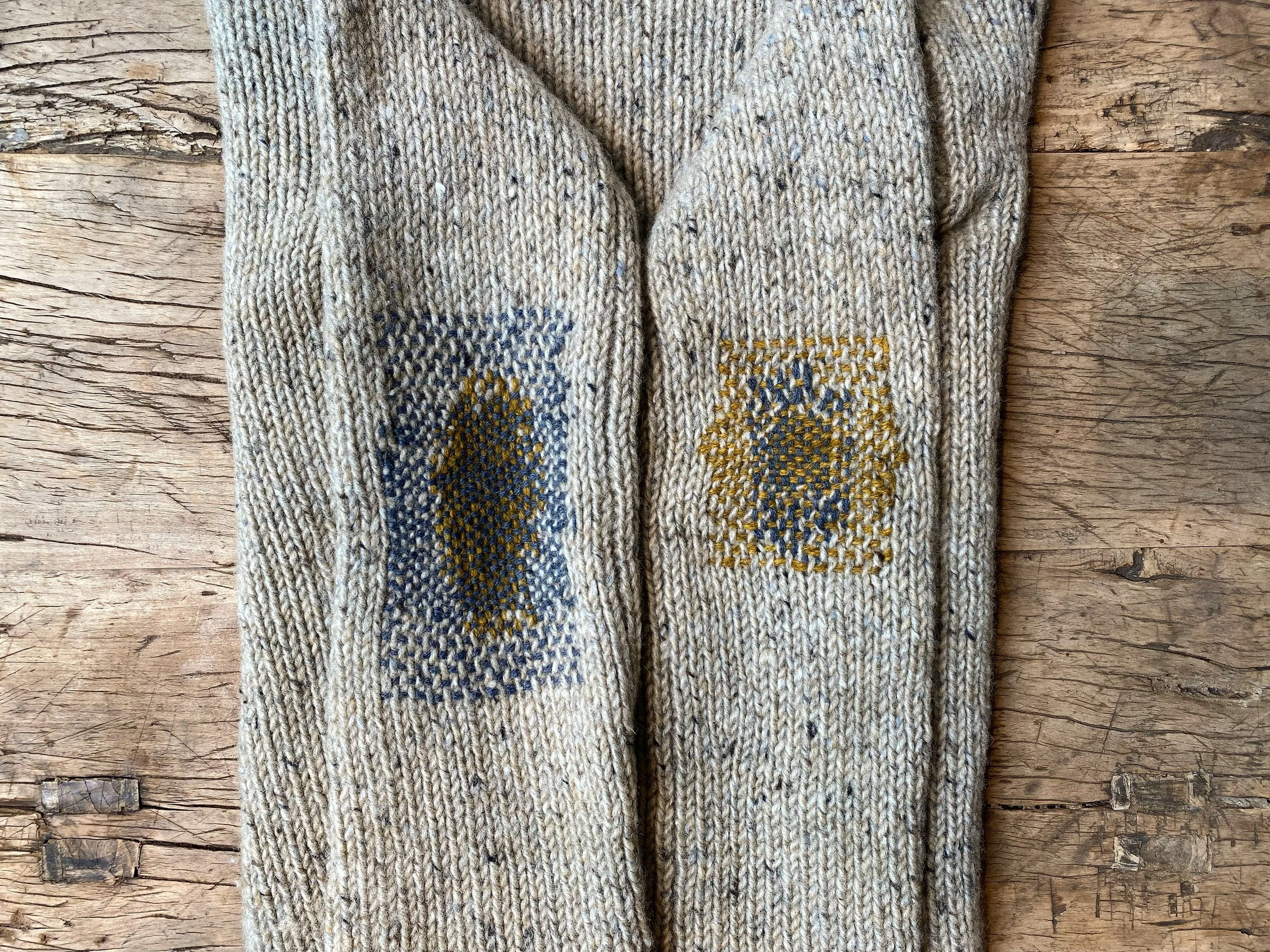 Visible repairs on knitted jumper; Both elbows mended with woven darns both in mustard and grey yarn on cream donegal knit