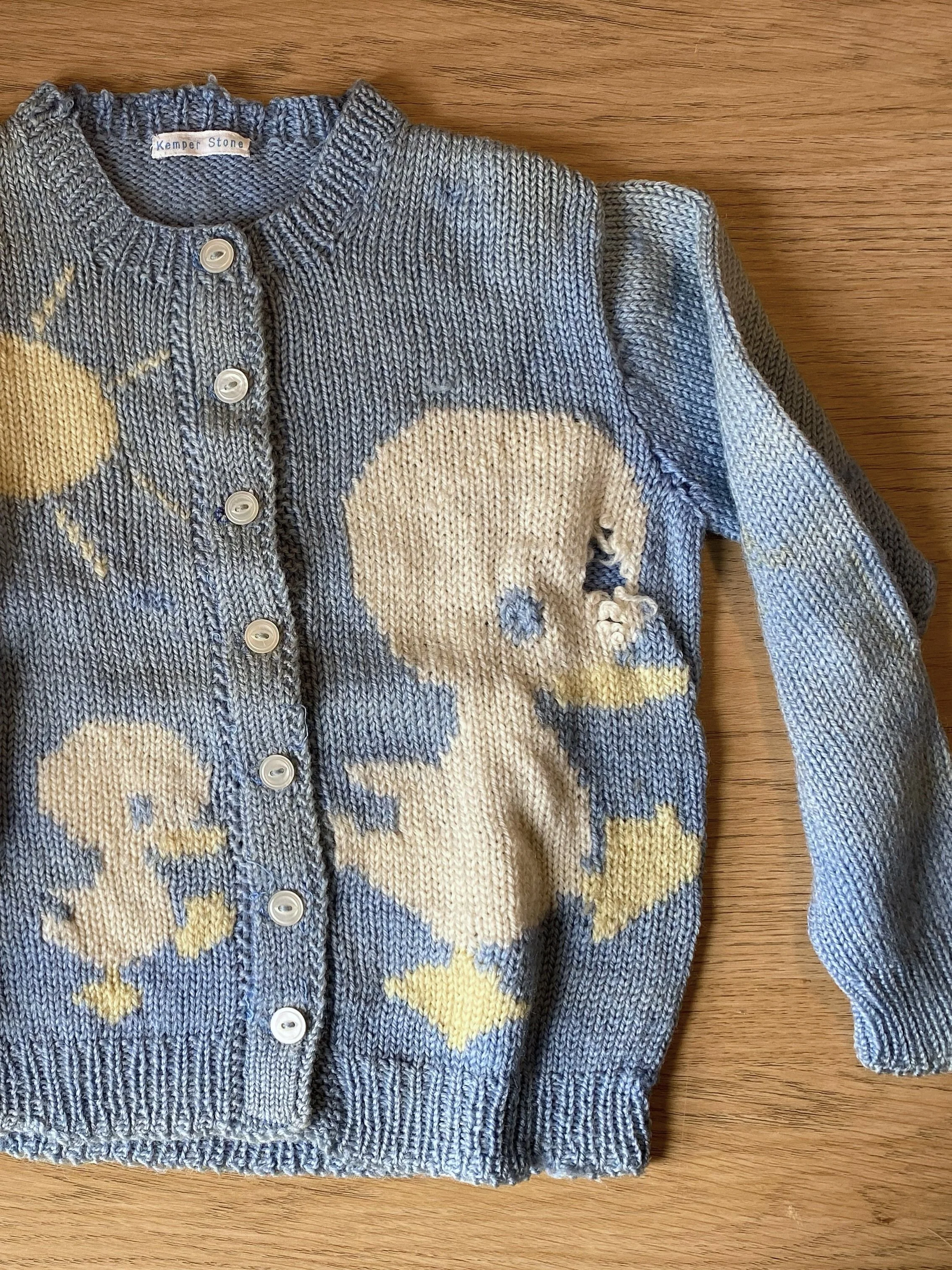 Damaged vintage children's cardigan with multiple holes and discolouration