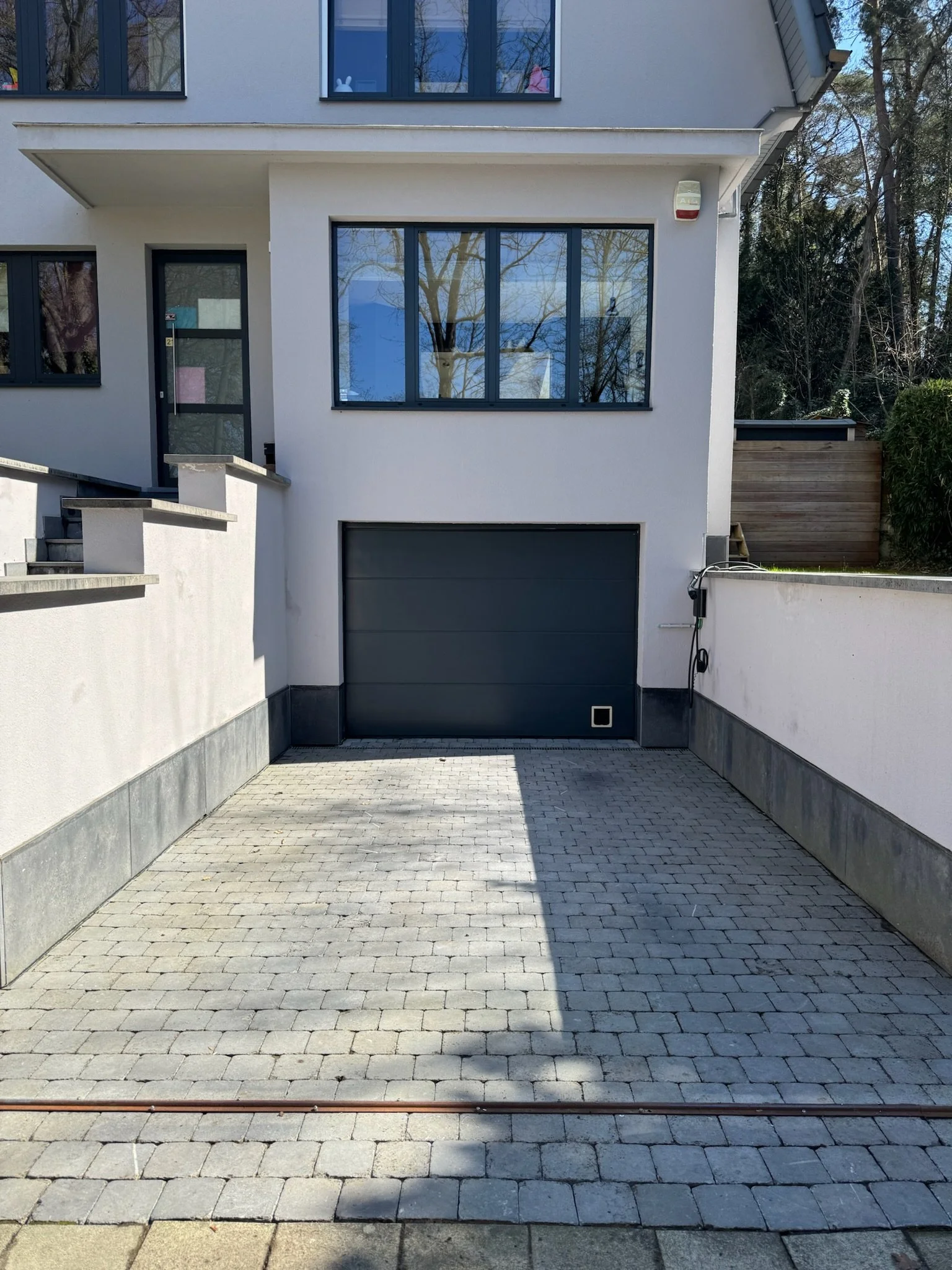 Façade d'une maison moderne avec garage dans une zone résidentielle.