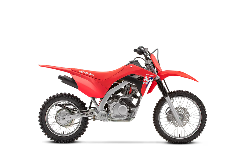 Red Honda dirt bike with knobby tires, black seat, and front suspension, viewed in profile against a plain background.