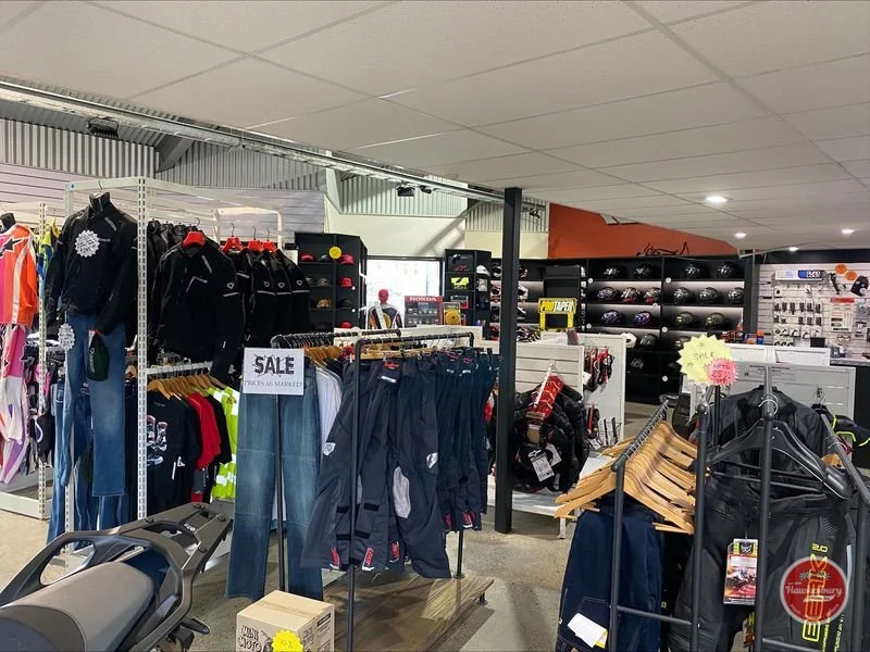 Clothing and accessories on sale inside sports store, including jackets, pants, helmets, and helmets, with sale signs.