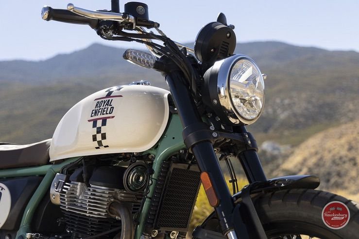 Close-up of a Royal Enfield motorcycle against a mountainous landscape.