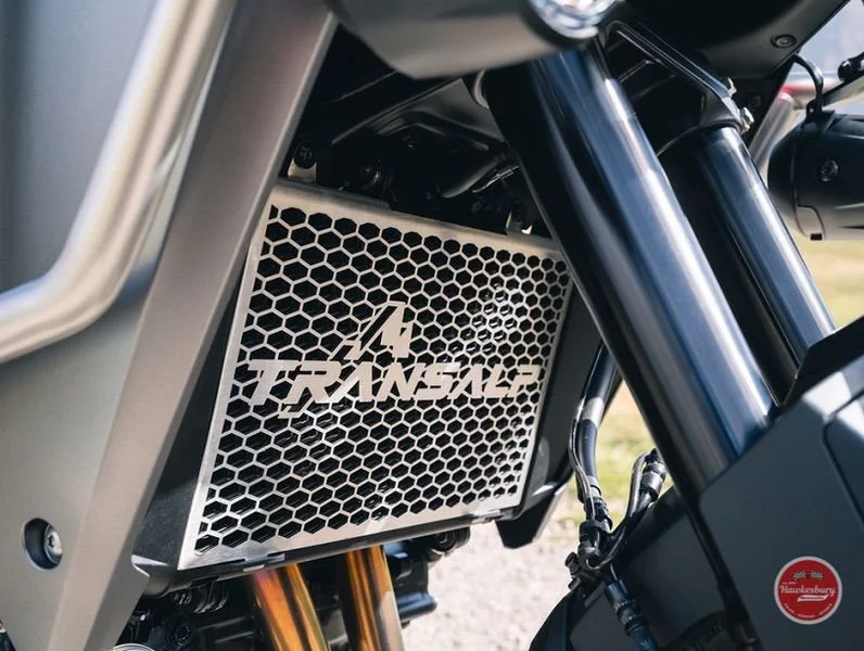 A close-up view of a motorcycle's radiator with the logo 'TRINACLE' on a honeycomb grille.