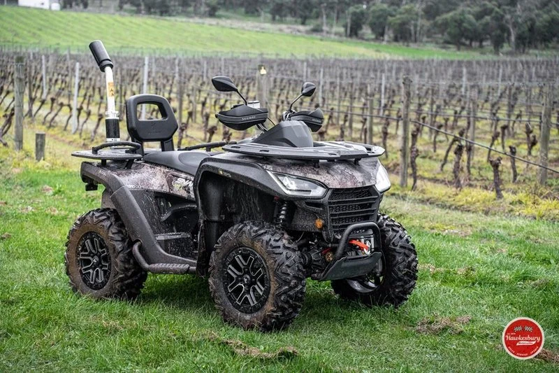 A Segway all-terrain vehicle (ATV) is parked on grass in a vineyard with rows of grapevines in the background.