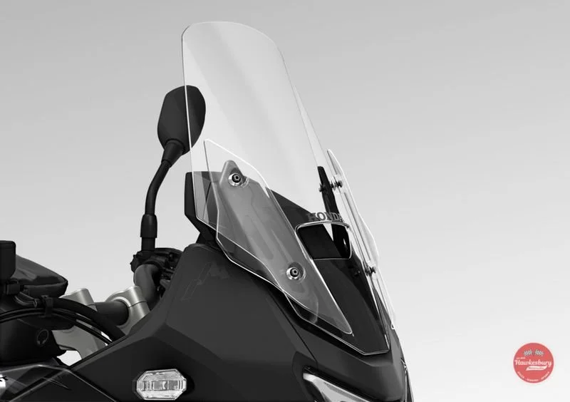 Close-up of a Honda motorcycle windscreen and handlebar with a rearview mirror, against a plain gray background.