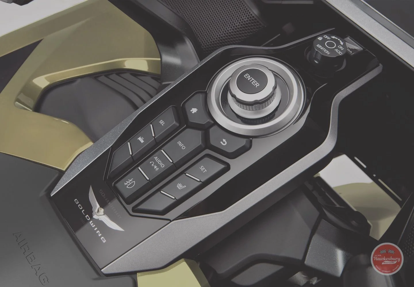 Close-up of a Lamborghini car's interior control panel with buttons, a large rotary knob labeled 'ENTER', and a clutch switch. The Lamborghini logo is visible on the dashboard.