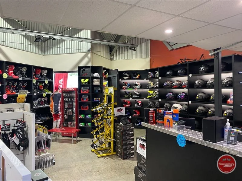 A motorcycle helmet display in a retail store, with helmets on shelves and various motorcycle accessories around.