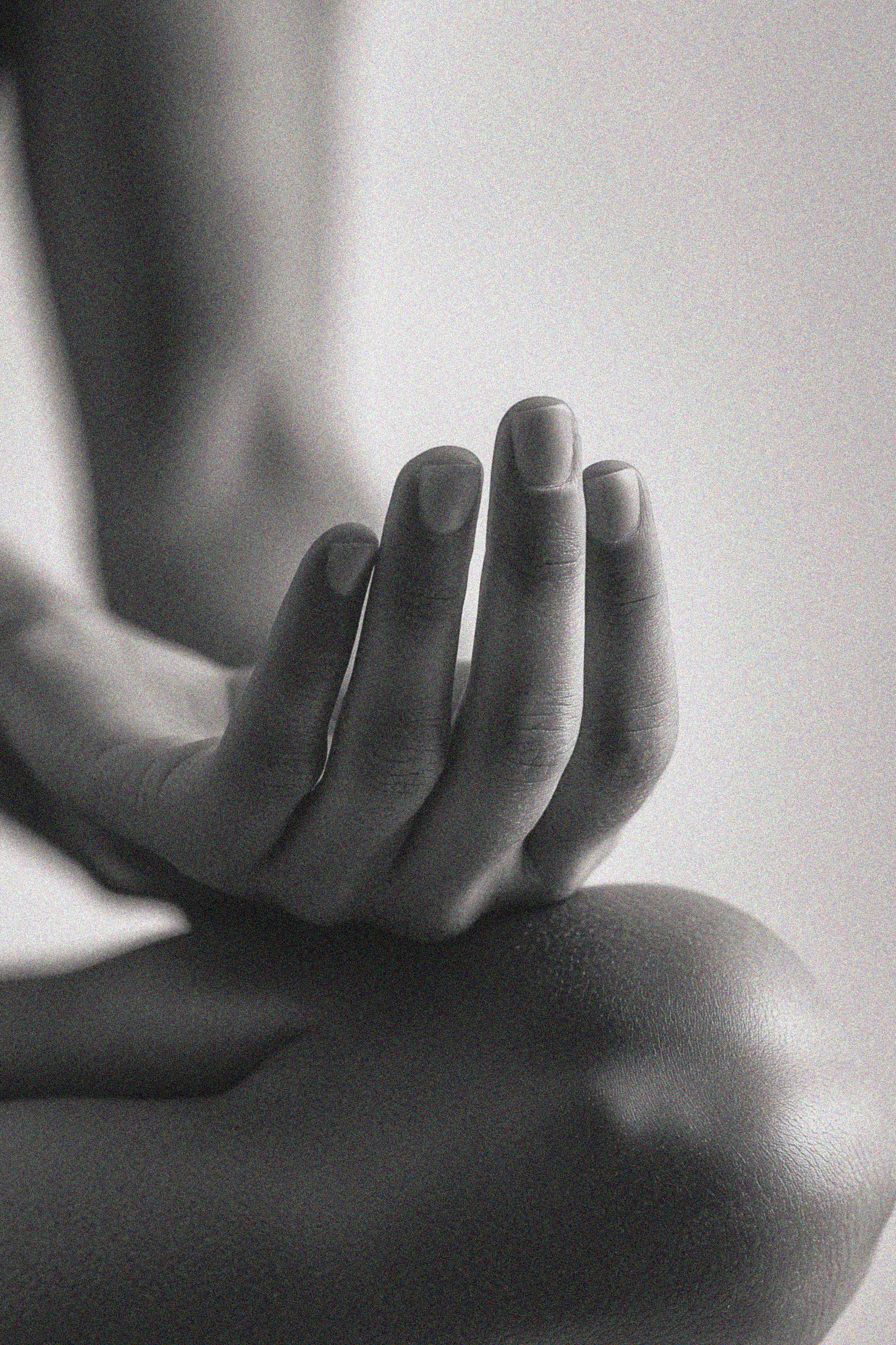 Close-up of a hand gently resting on a knee in grayscale.