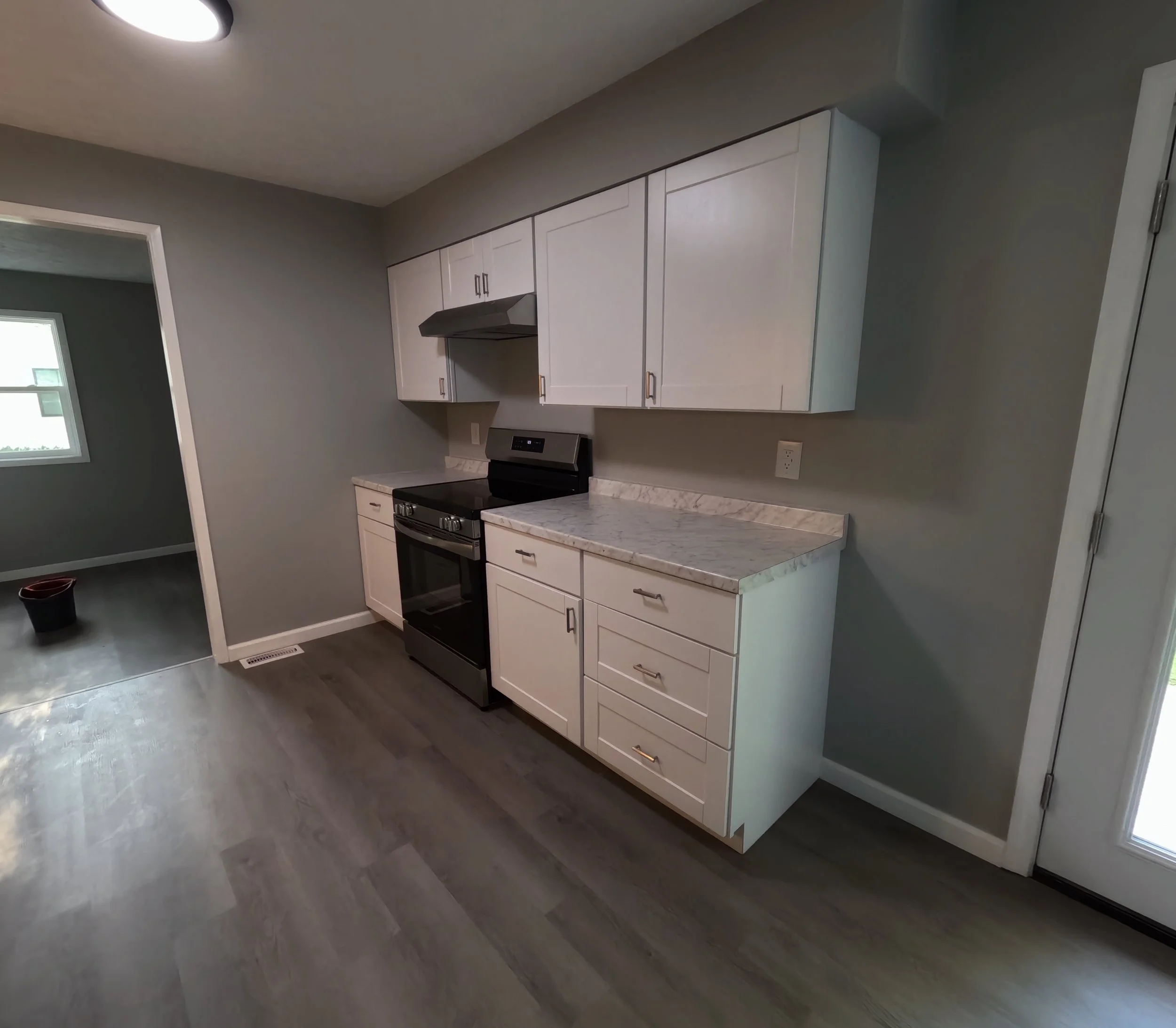 A modern kitchen with white cabinets, a marble countertop, and a black stove We serve homeowners and businesses in Madison, Hanover, Scottsburg, Austin, Milton, KY, Carrollton, KY and surrounding communities throughout Jefferson County, Scott County,