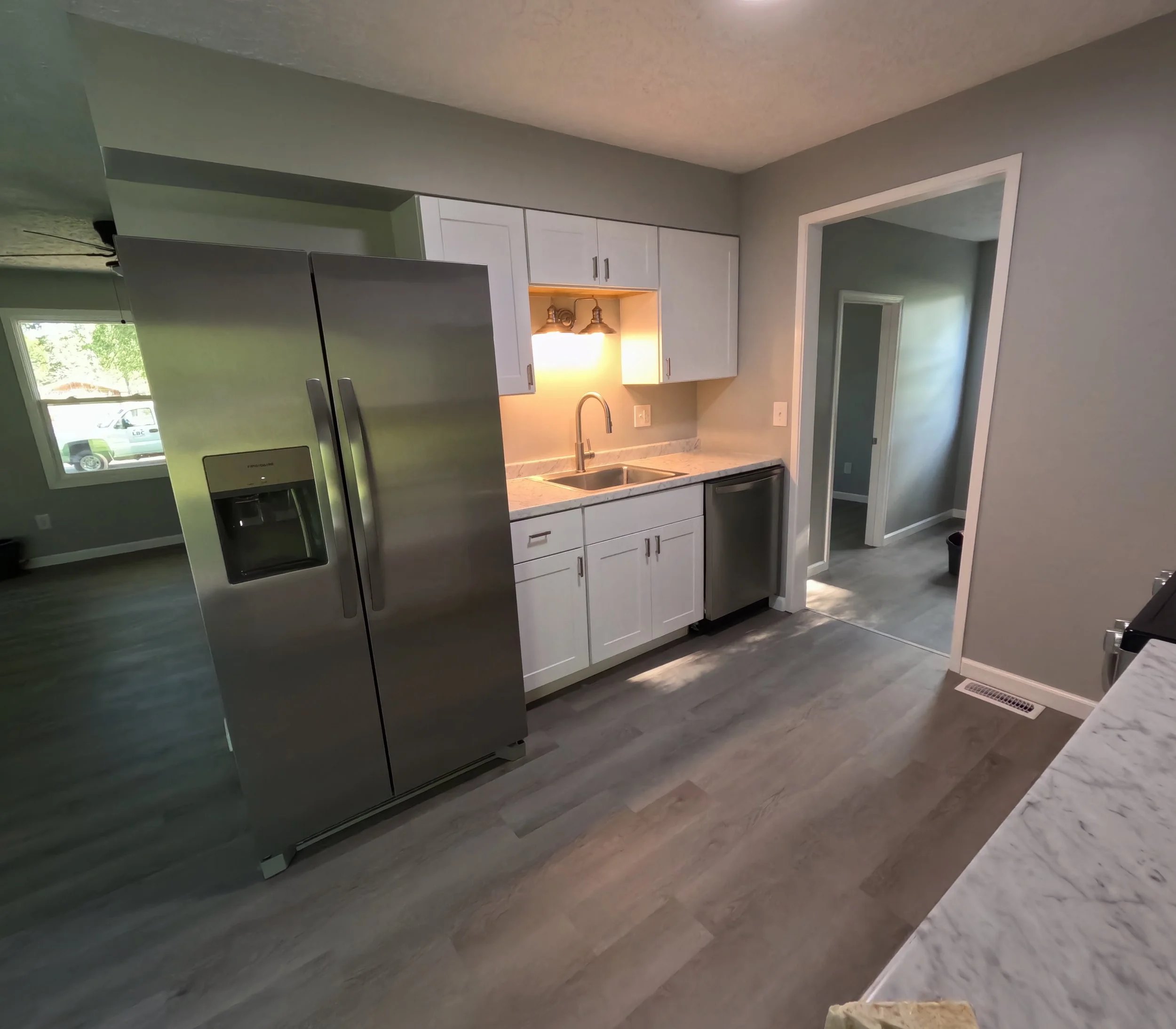 Modern kitchen with stainless steel refrigerator, white cabinets, marble countertops, and a double sink, We serve homeowners and businesses in Madison, Hanover, Scottsburg, Austin, Milton, KY, Carrollton, KY and surrounding communities throughout