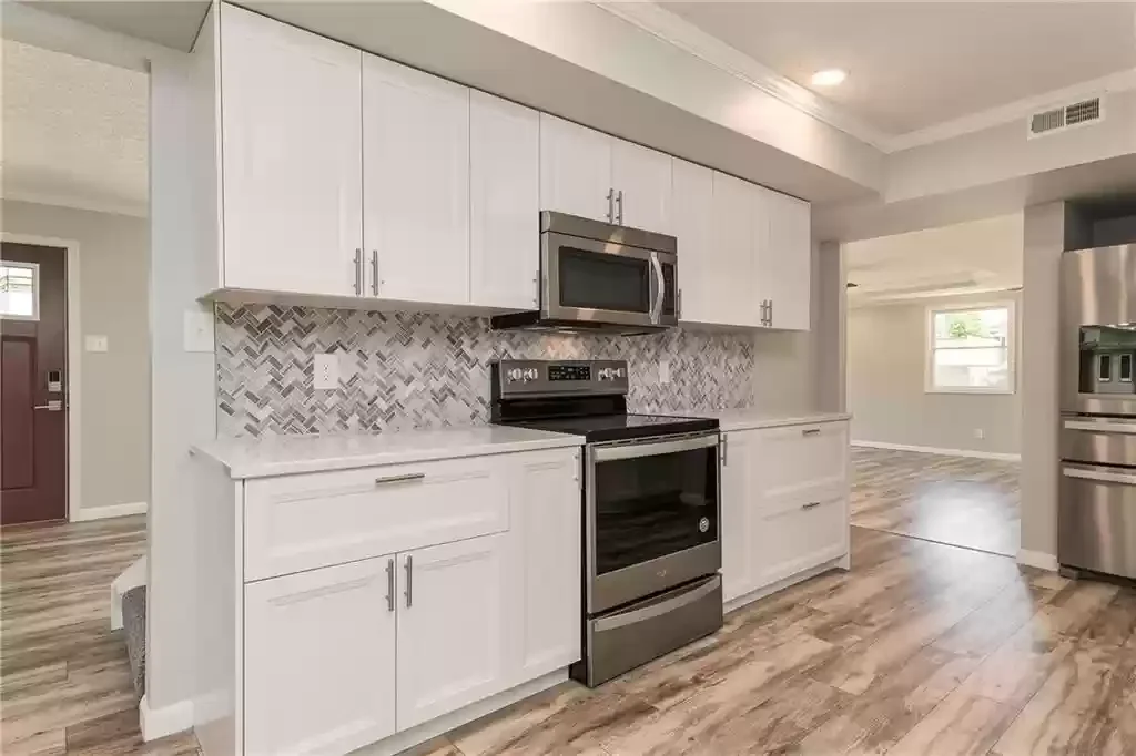 Modern kitchen with white cabinets, stainless steel appliances, and a herringbone-patterned tile backsplash. We serve homeowners and businesses in Madison, Hanover, Scottsburg, Austin, Milton, KY, Carrollton, KY and surrounding communities throughout