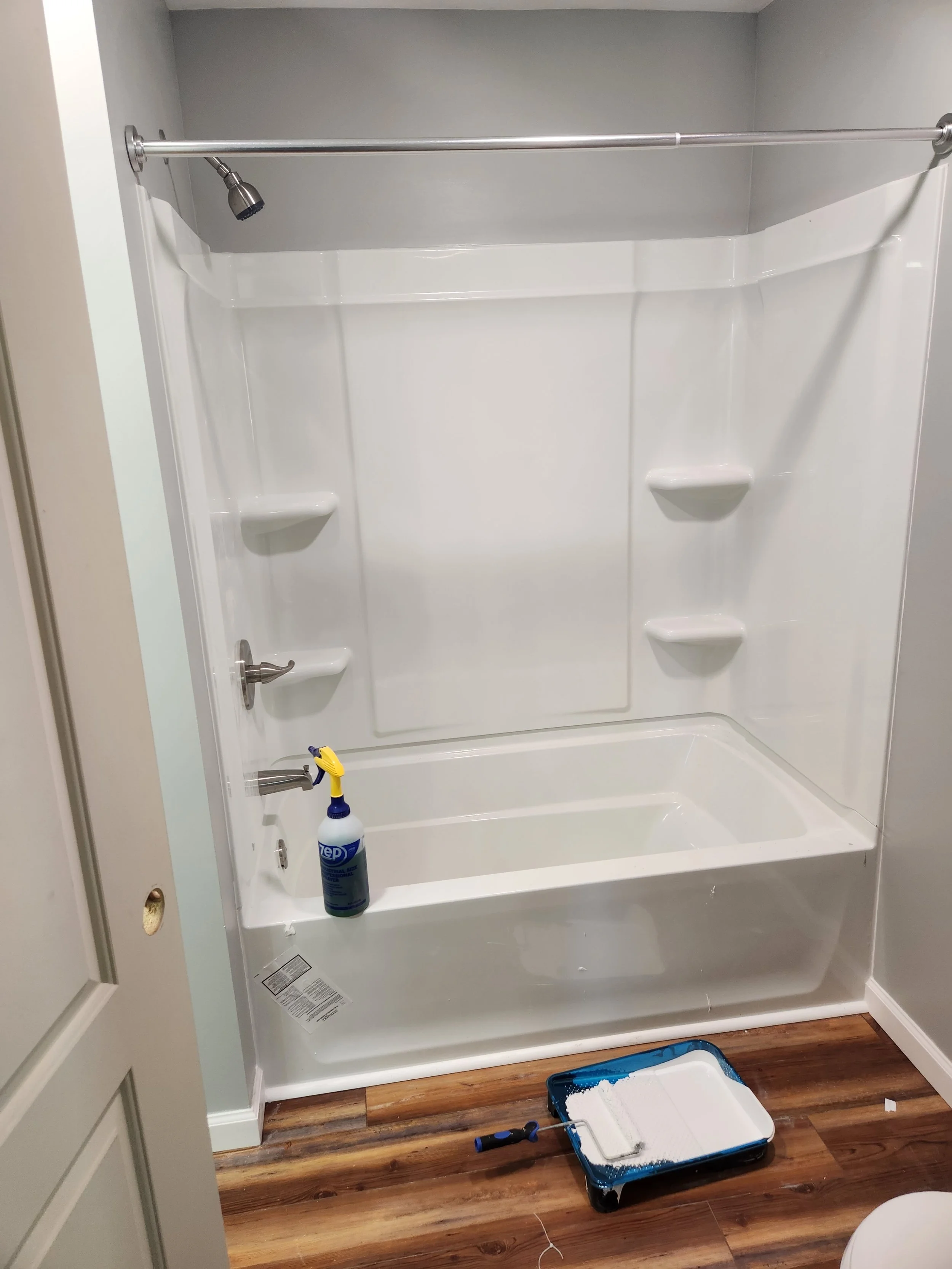 A white bathtub and shower area with a showerhead, faucet, and built-in shelves, We serve homeowners and businesses in Madison, Hanover, Scottsburg, Austin, Milton, KY, Carrollton, KY and surrounding communities throughout Jefferson County 