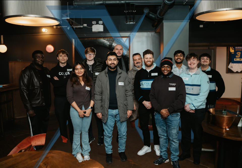 Group of eleven people standing inside a bar or restaurant, smiling for the photo, with warm lighting and modern decor.
