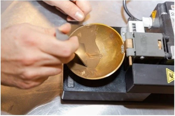 Persoon die een gouden ring giet in een gieterij, met gebruik van een mal en een smeltoven.