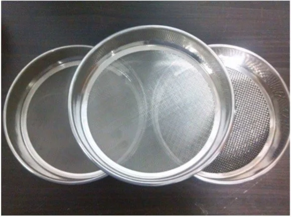 Vier zilveren bakvormen of filters, plat en rond, op een donkere tafel.