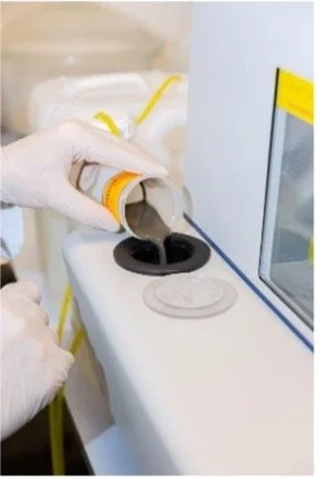 Persoon in laboratorium hand die een buisje met vloeistof vasthoudt en een pipet gebruikt boven een laboratoriumkastje.