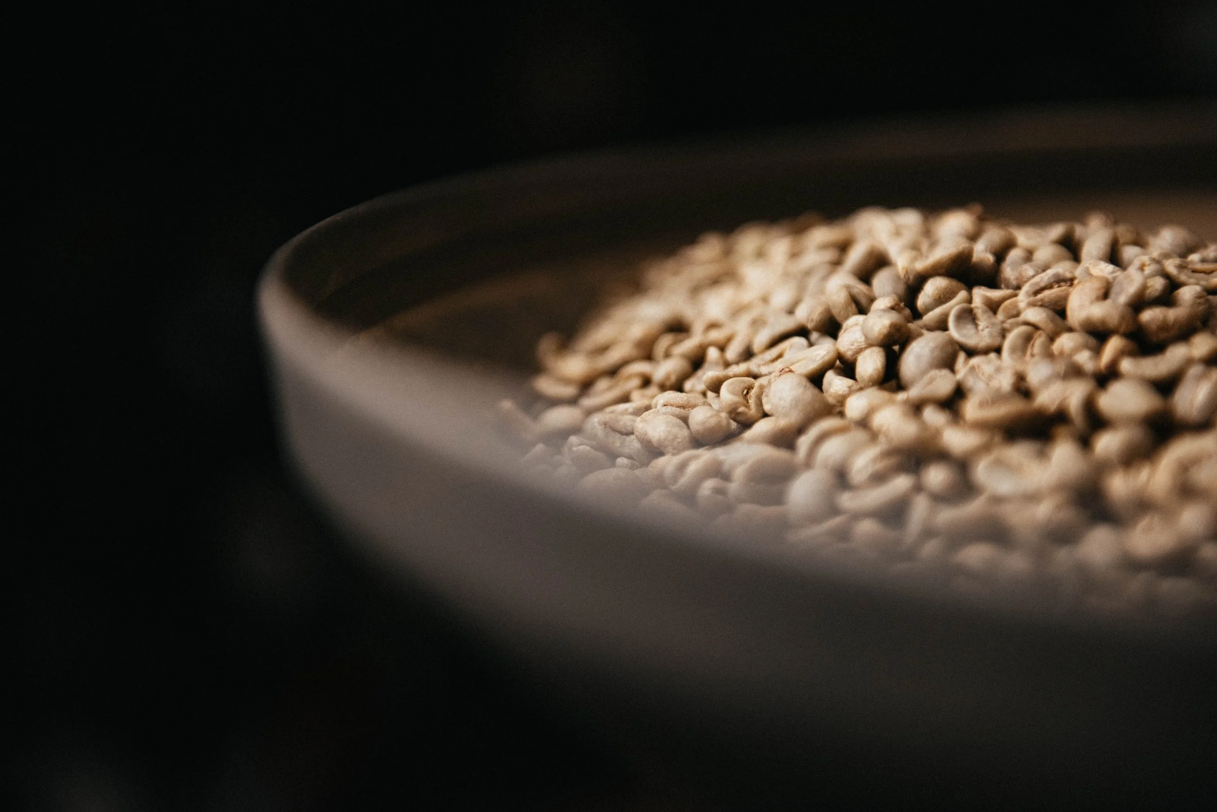 Close-up of a bowl filled with coffee beans on a dark background