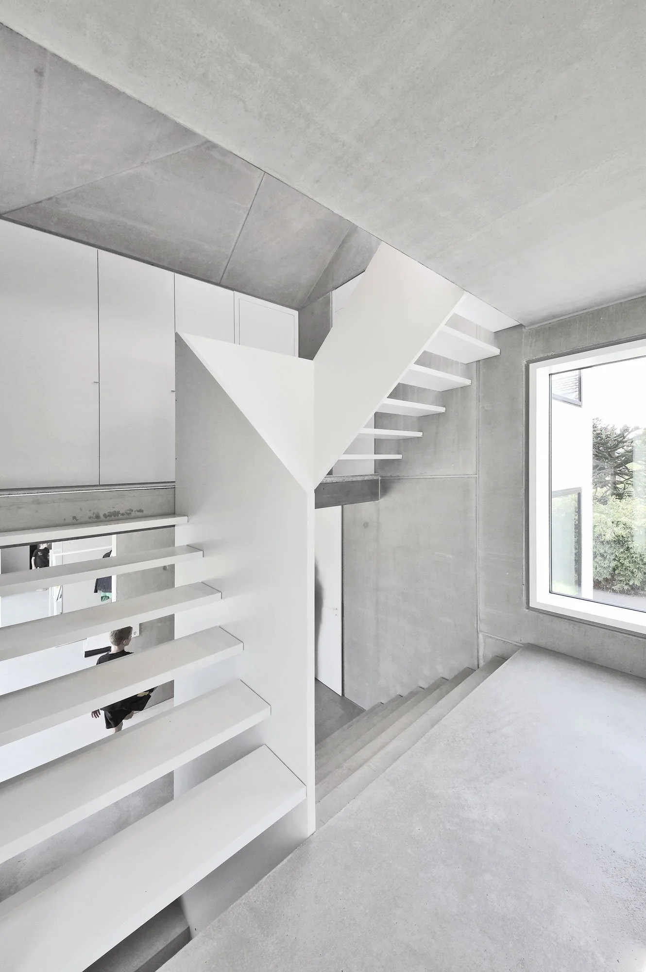 haus SG - Moderne, minimalistische Treppen in einem hellen, offenen Raum mit großen Fenstern, betonierter Wand und weißem Oberflächendesign.