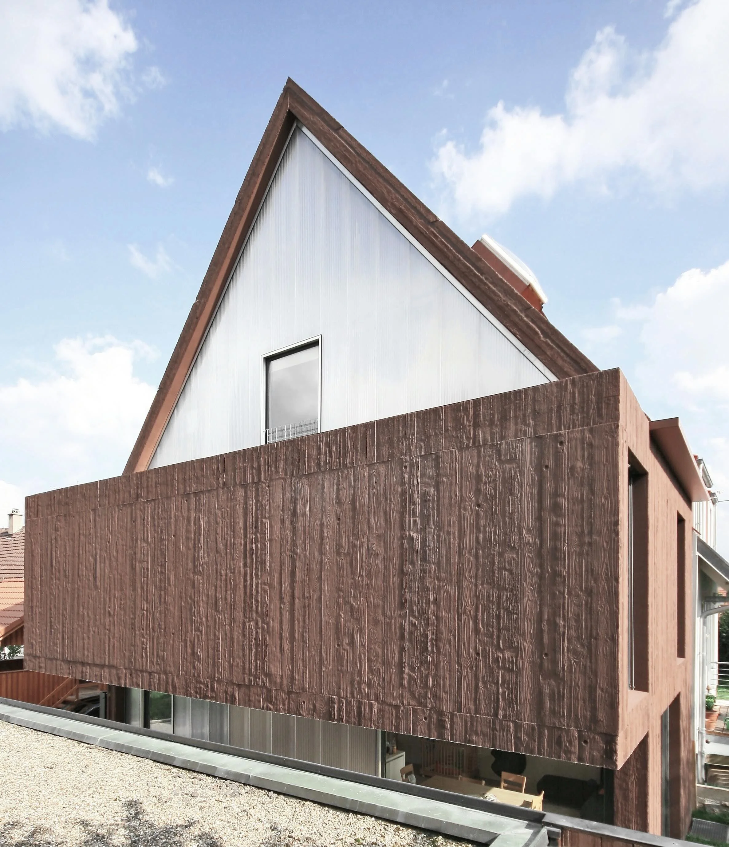 haus - B_Modernes Wohnhaus mit steilem Satteldach, Holzfassade und großen Fenstern vor blauem Himmel