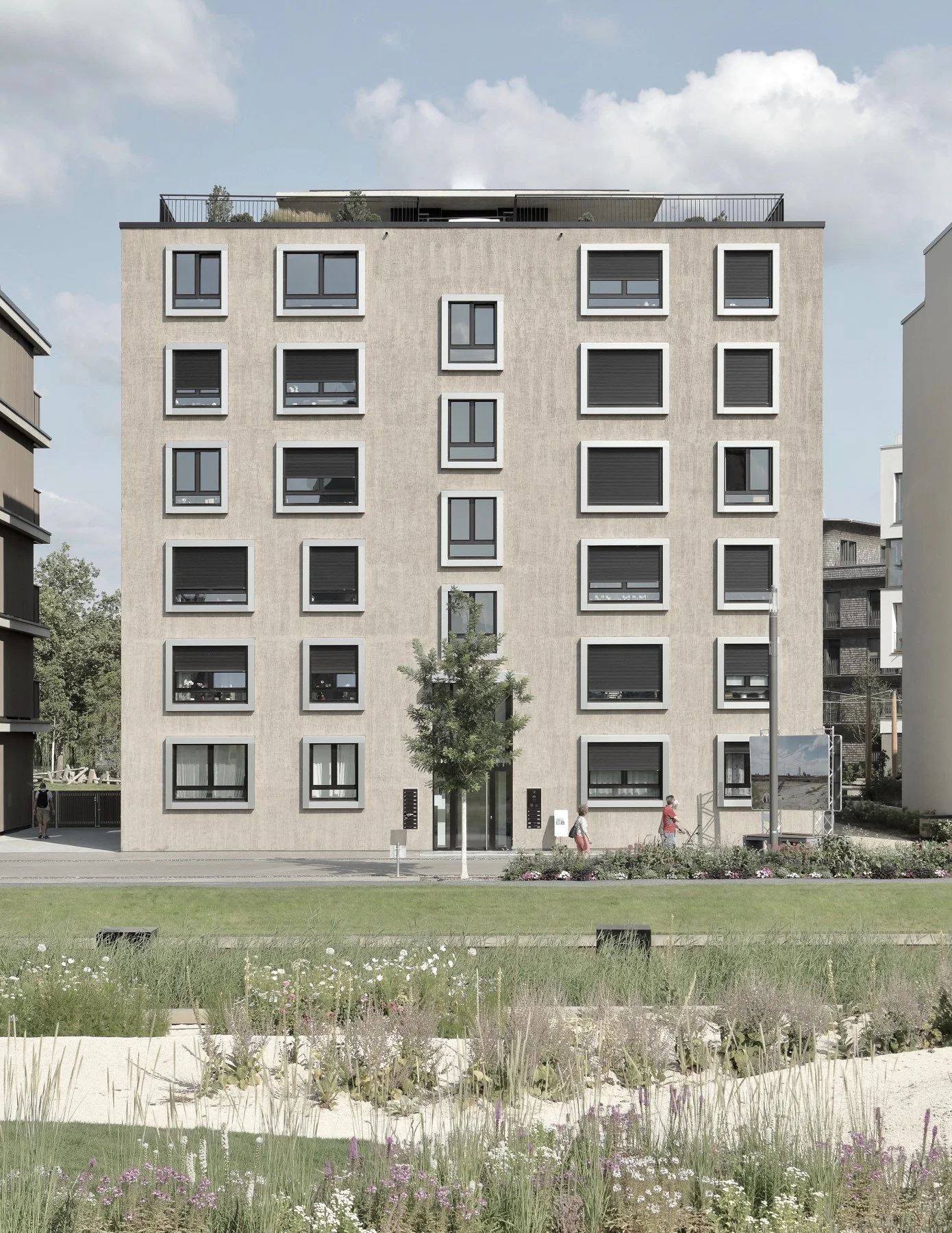 wohnhaus BUGA - Mehrstöckiges modernes Wohngebäude mit großen Fenstern und Dachgarten, umgeben von Grünflächen und Menschen beim Spaziergang.