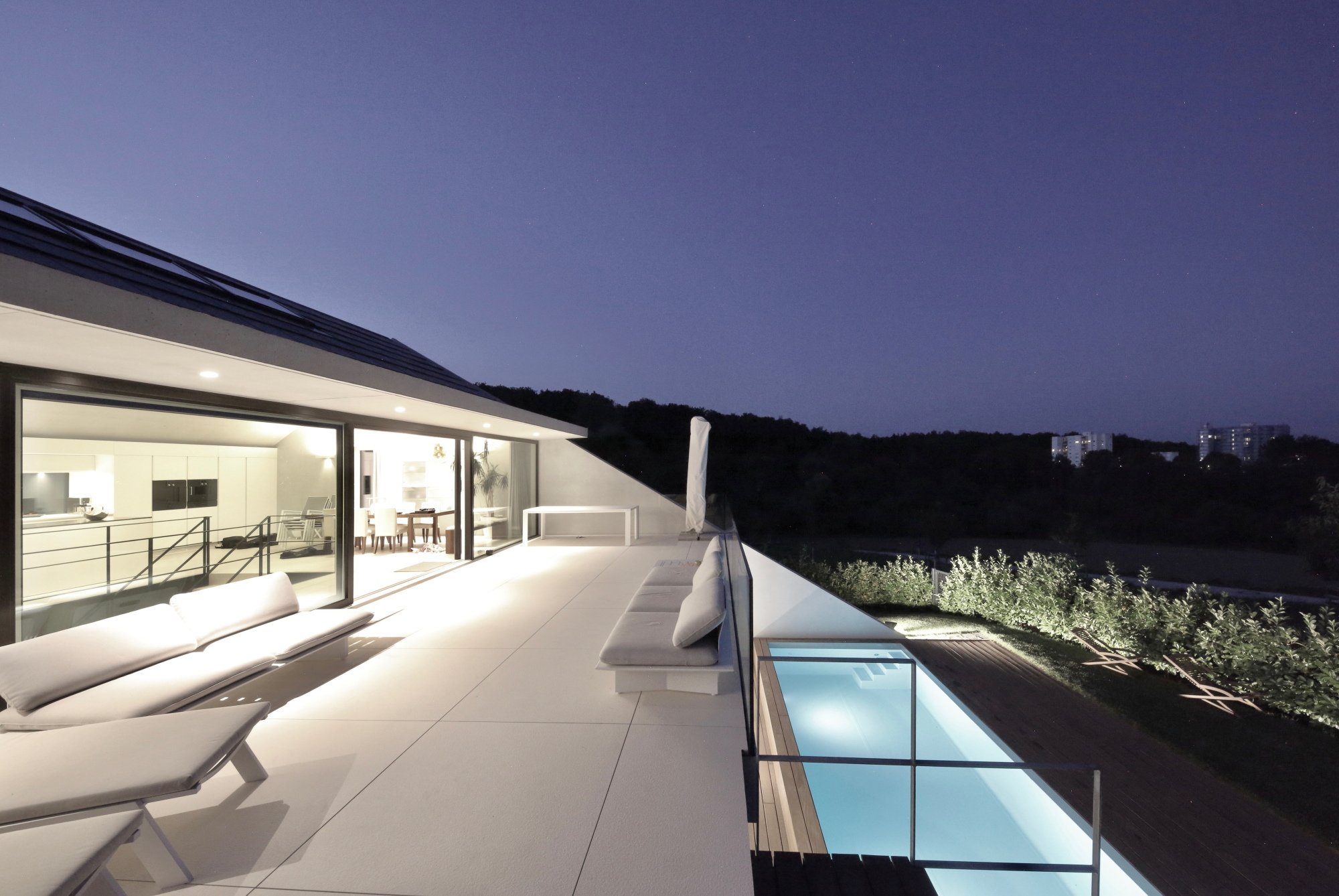 haus CC - Moderne Dachterrasse bei Nacht mit Sitzmöbeln, Glasgeländer und Blick auf nächtliche Stadt und Natur.