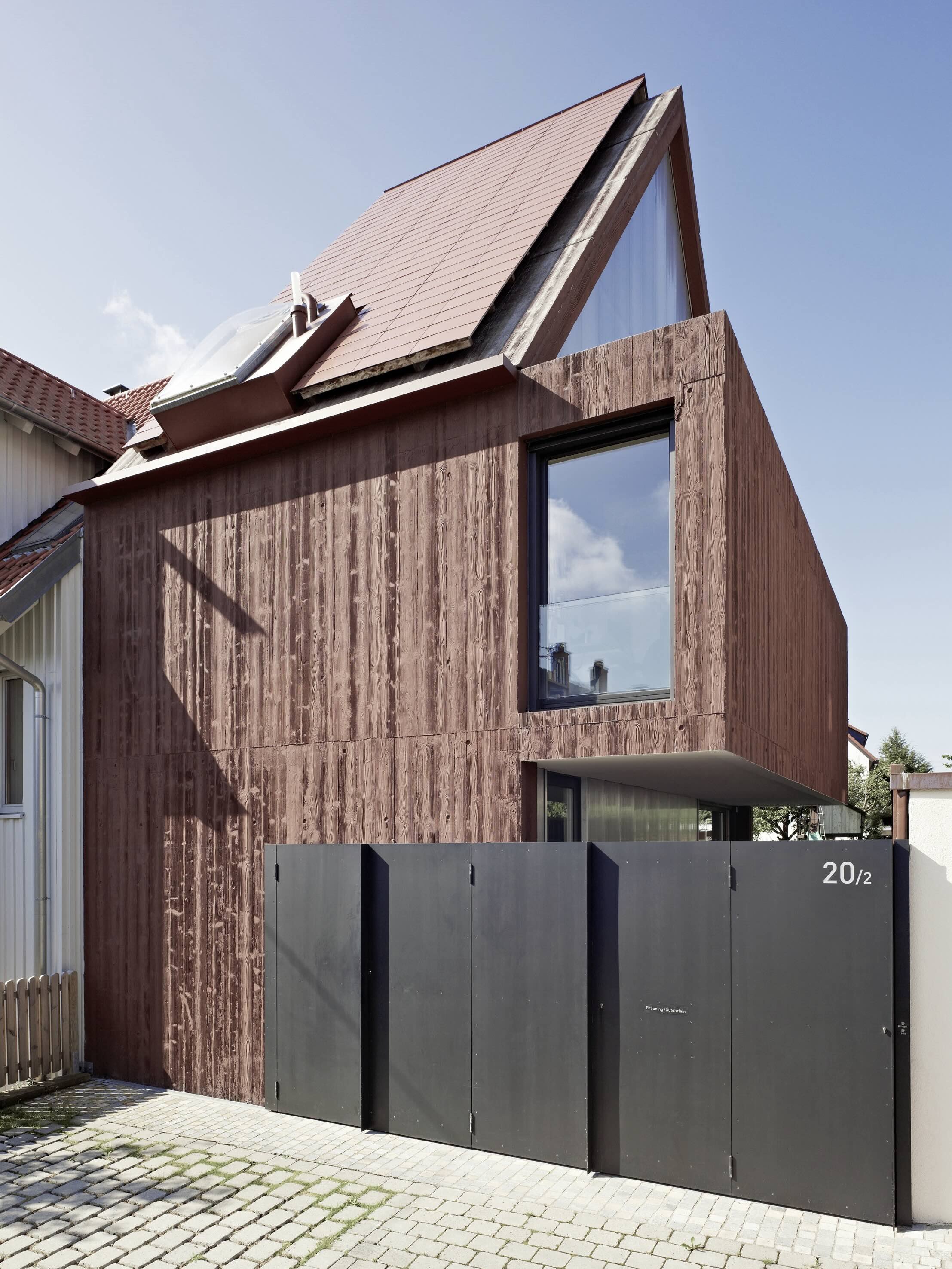 haus - B_Modernes Wohnhaus mit markantem Satteldach, brauner Holzfassade, großen Fenstern und schwarzem Hoftor