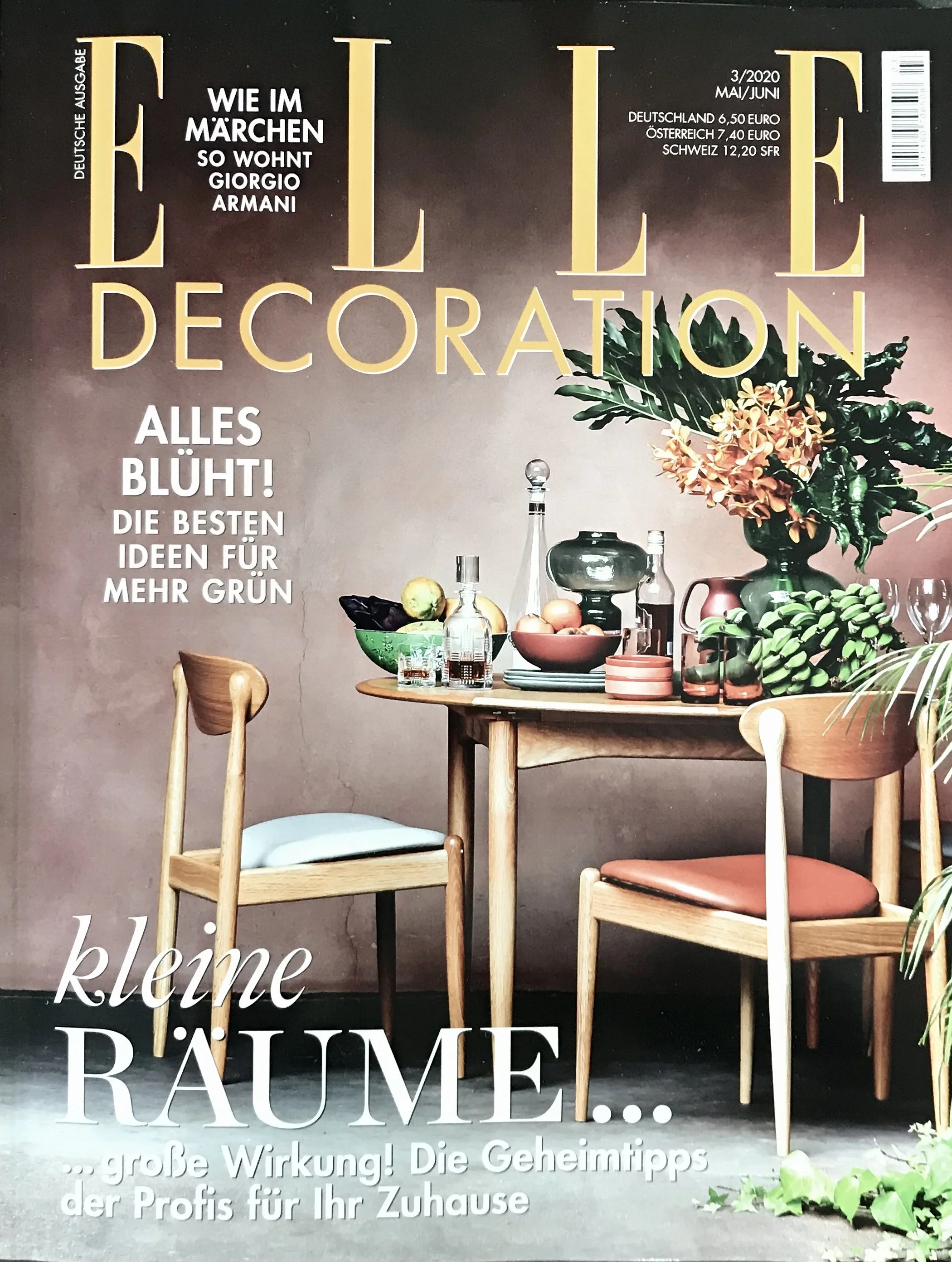 Titel der Zeitschrift 'ELLE Decoration' mit Einrichtungstisch, Stühlen, Vasen und Blumen im Hintergrund, Text in Deutsch über Tipps für die Gestaltung des Zuhauses.