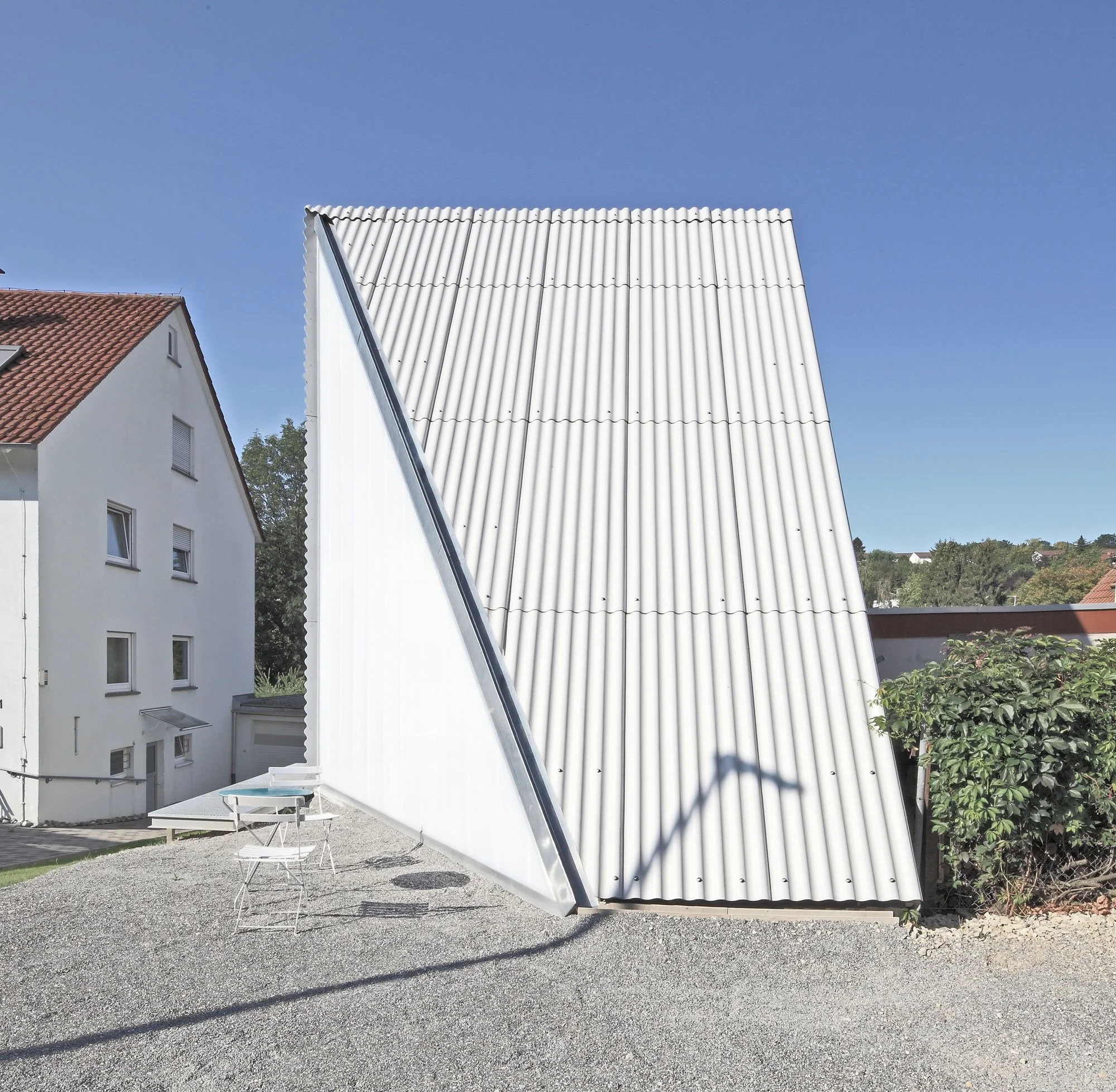 haus SO - Kieshof im Hintergrund Bäume und ein blauer Himmel.