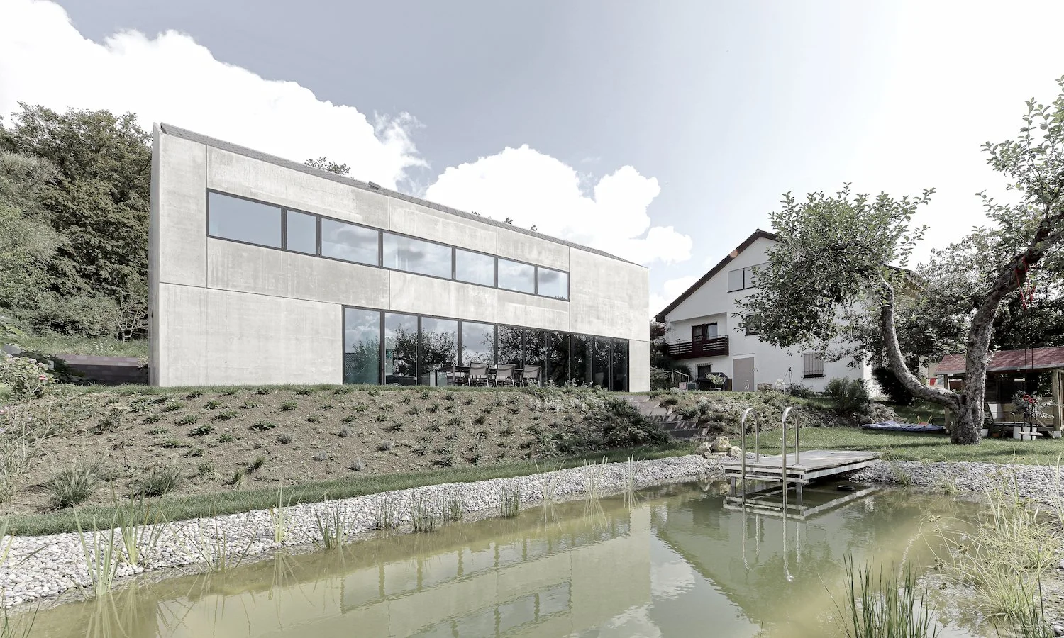 haus WÄ - Moderne, zweistöckige Haus mit großen Glasfenstern, im Garten mit Teich und Bäumen