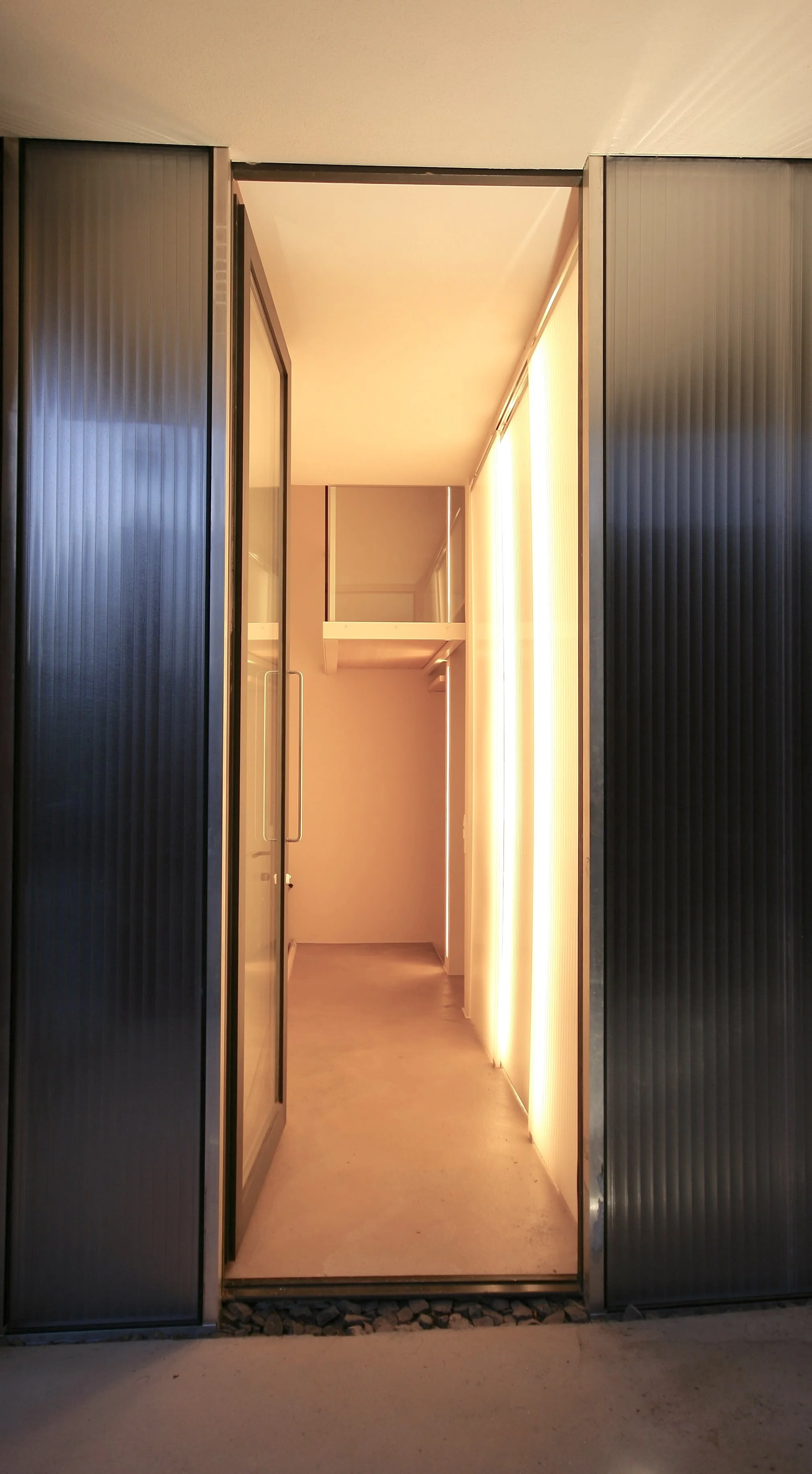 haus - B_Beleuchteter Innenflur mit geöffneten Glastüren und vertikalen Jalousien
