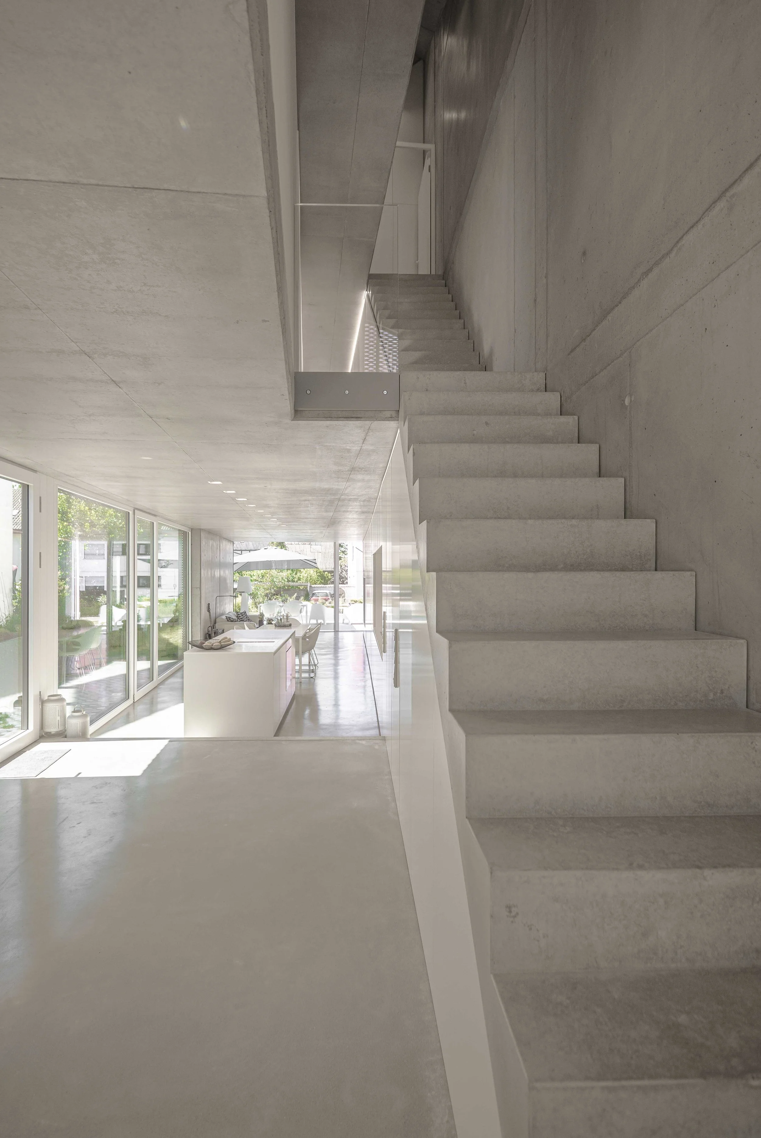 Innenansicht eines modernen, minimalistischen Hauses mit offenen Grundriss, viel natürlichem Licht und einer offenen Küche und Essbereich.
