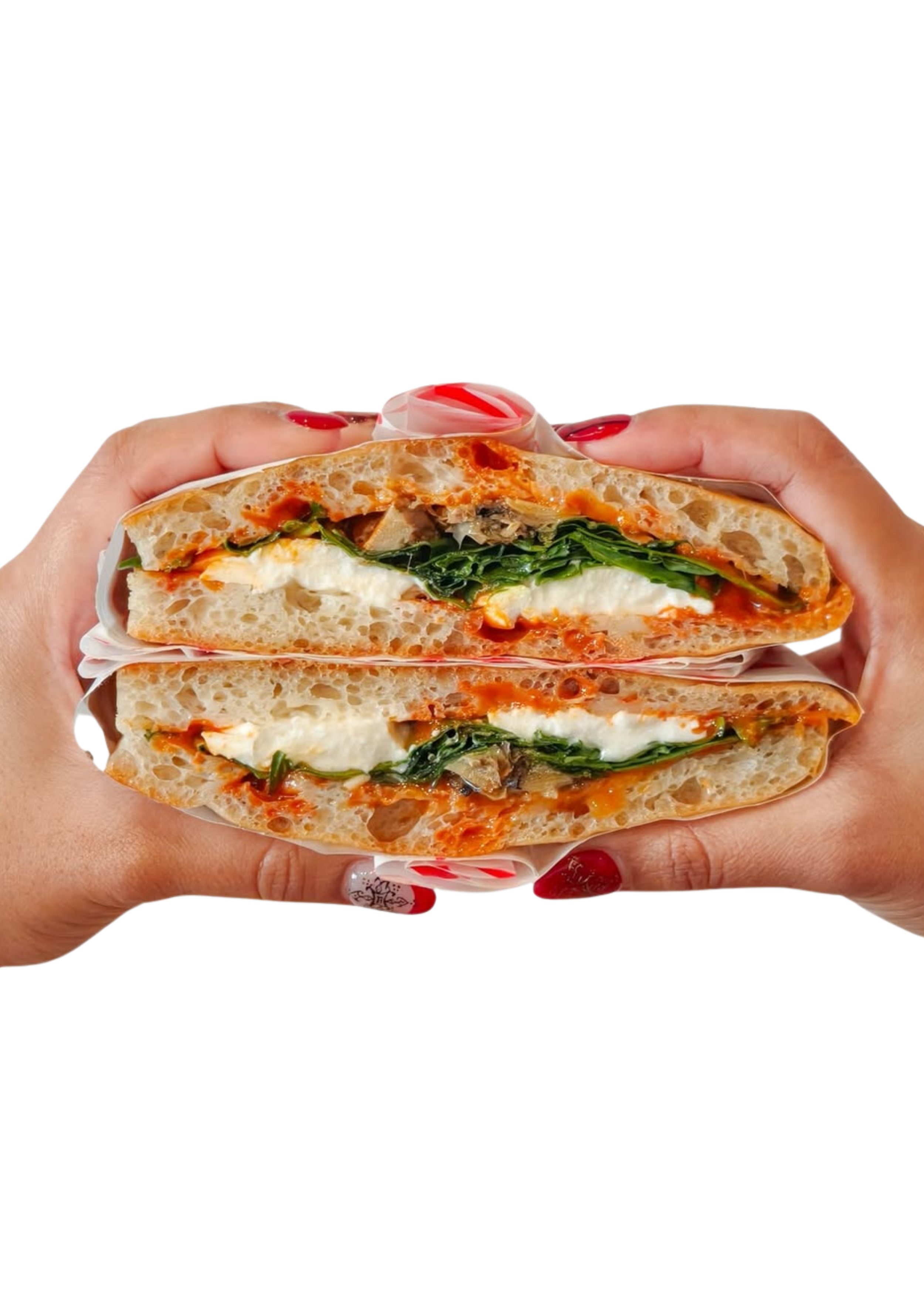 Deux mains tenant une sandwich coupé en deux, contenant du pain, du fromage, des légumes verts et de la sauce.