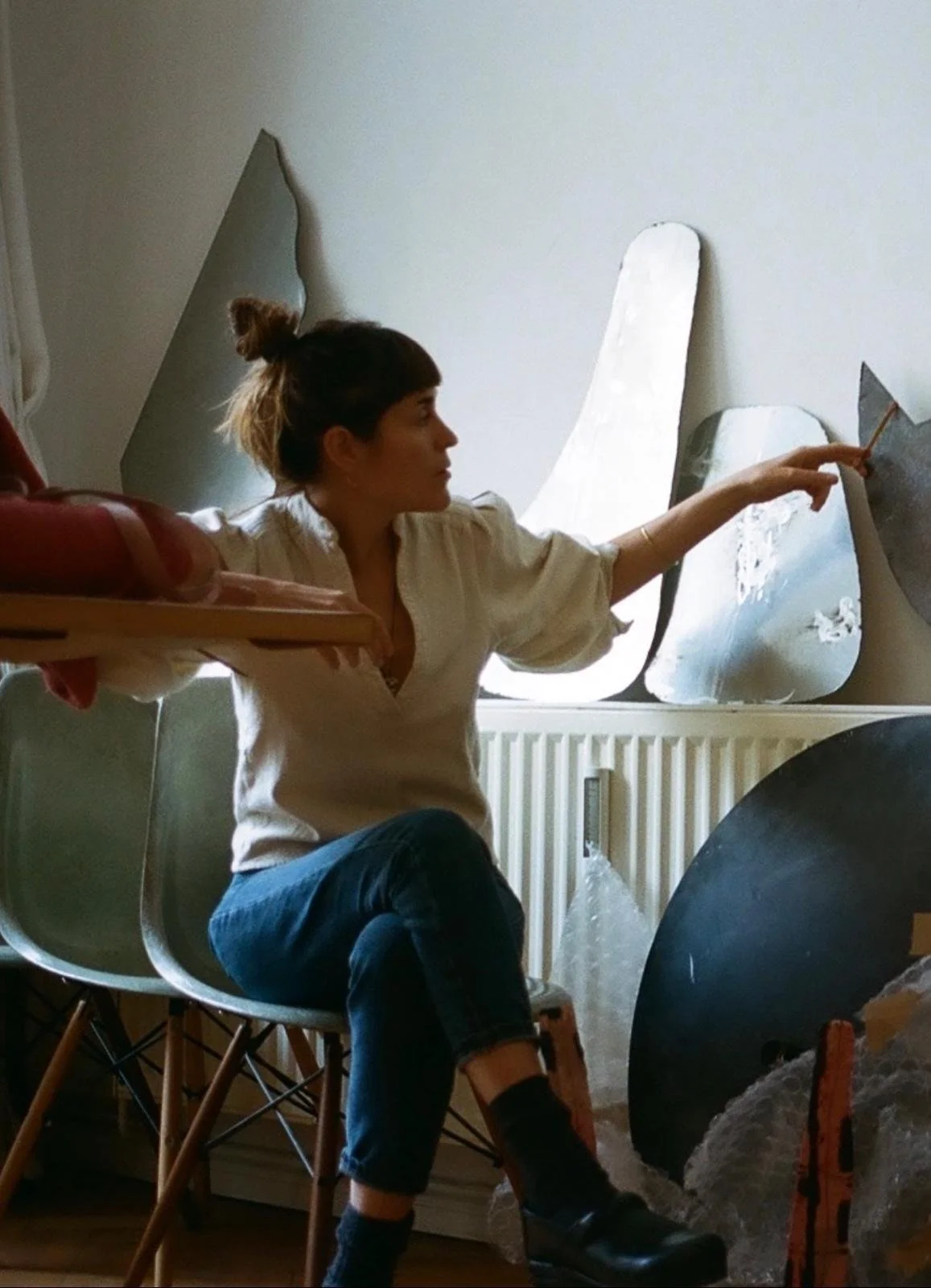 Woman sitting in a chair and pointing at abstract artwork displayed in a room