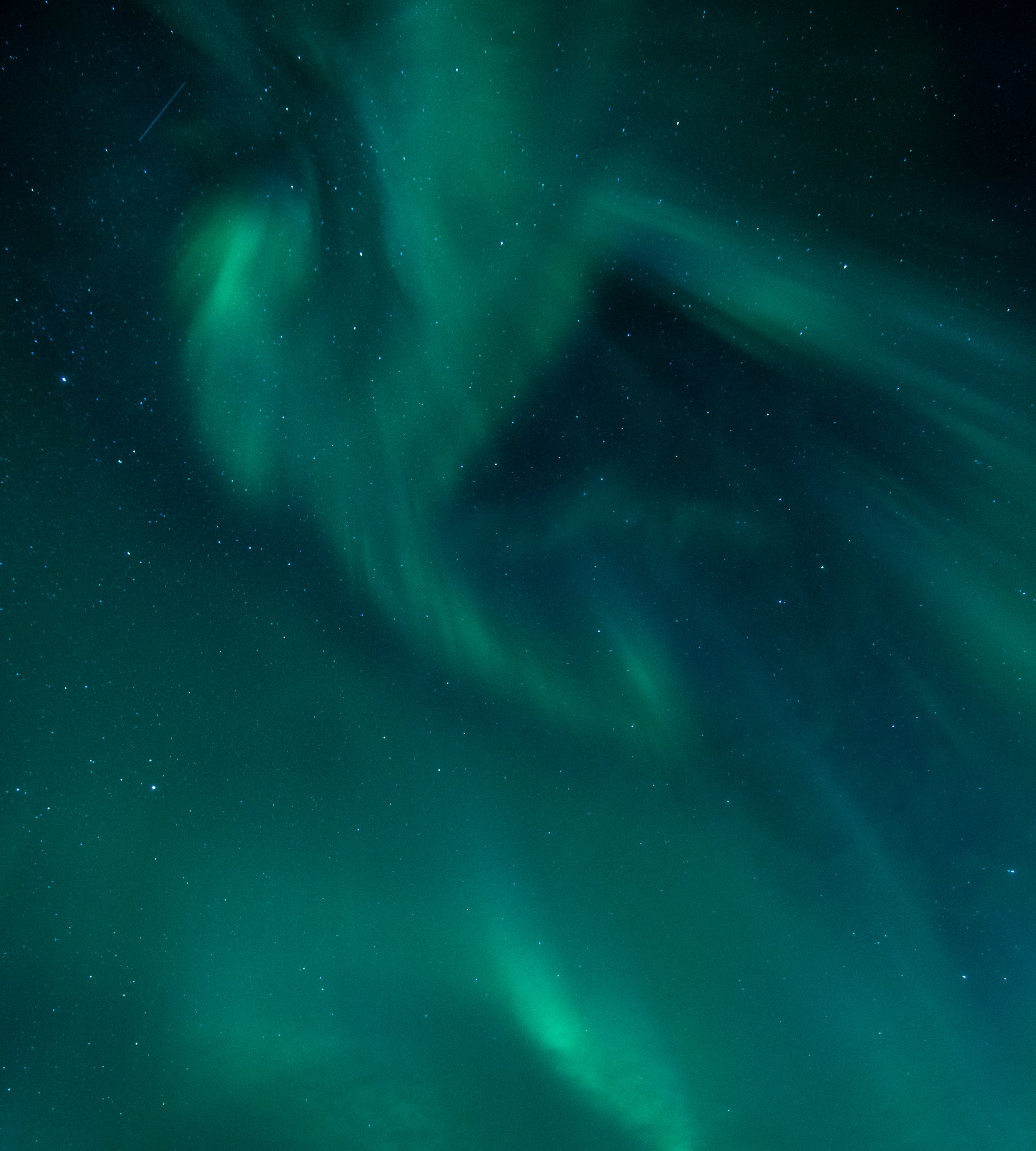 Northern Lights over a dark Arctic landscape in Northern Norway, near Tromsø