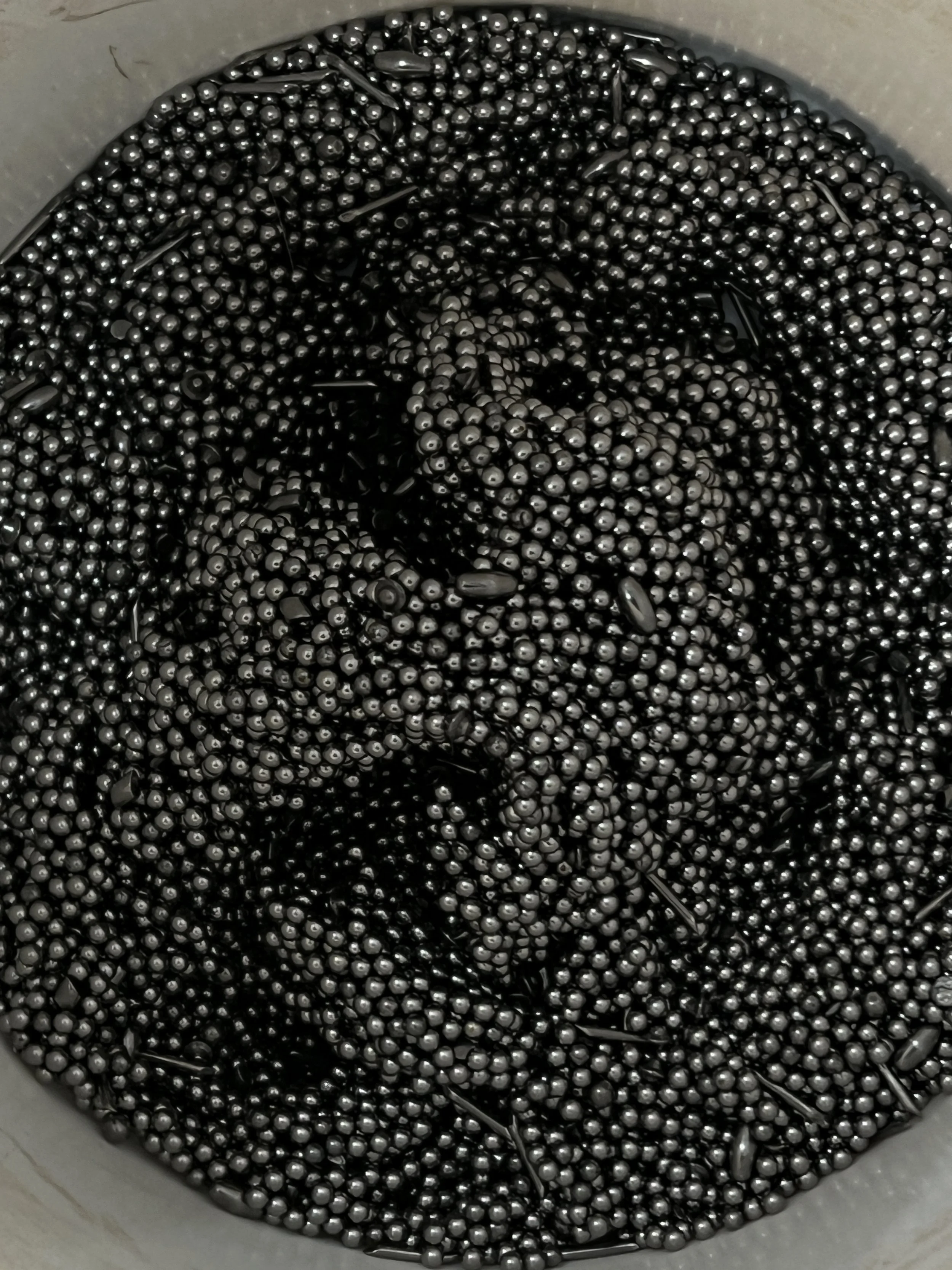 Close-up of numerous small metallic beads inside a container.