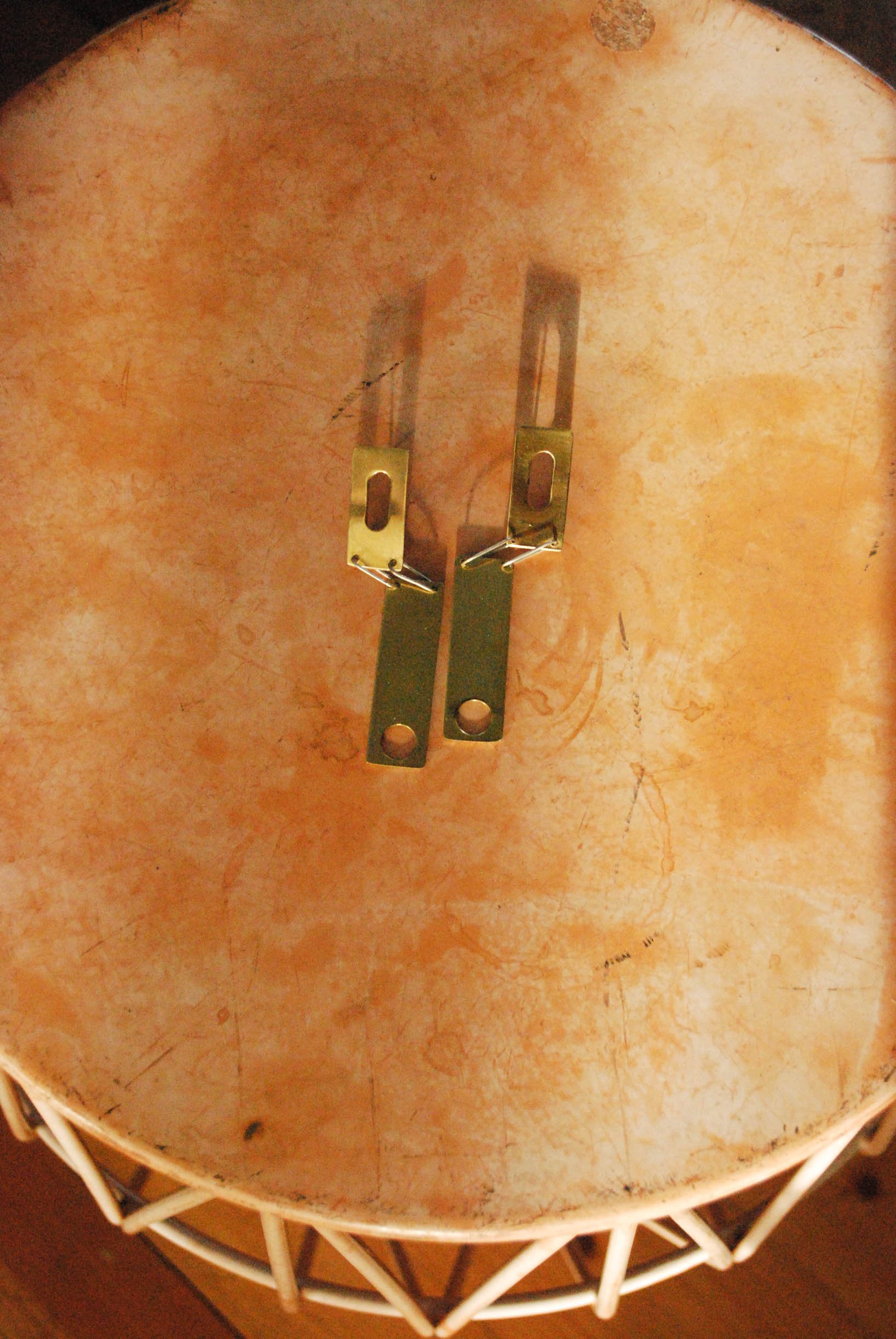 Back of a drum with metal lugs and a beige, textured surface.