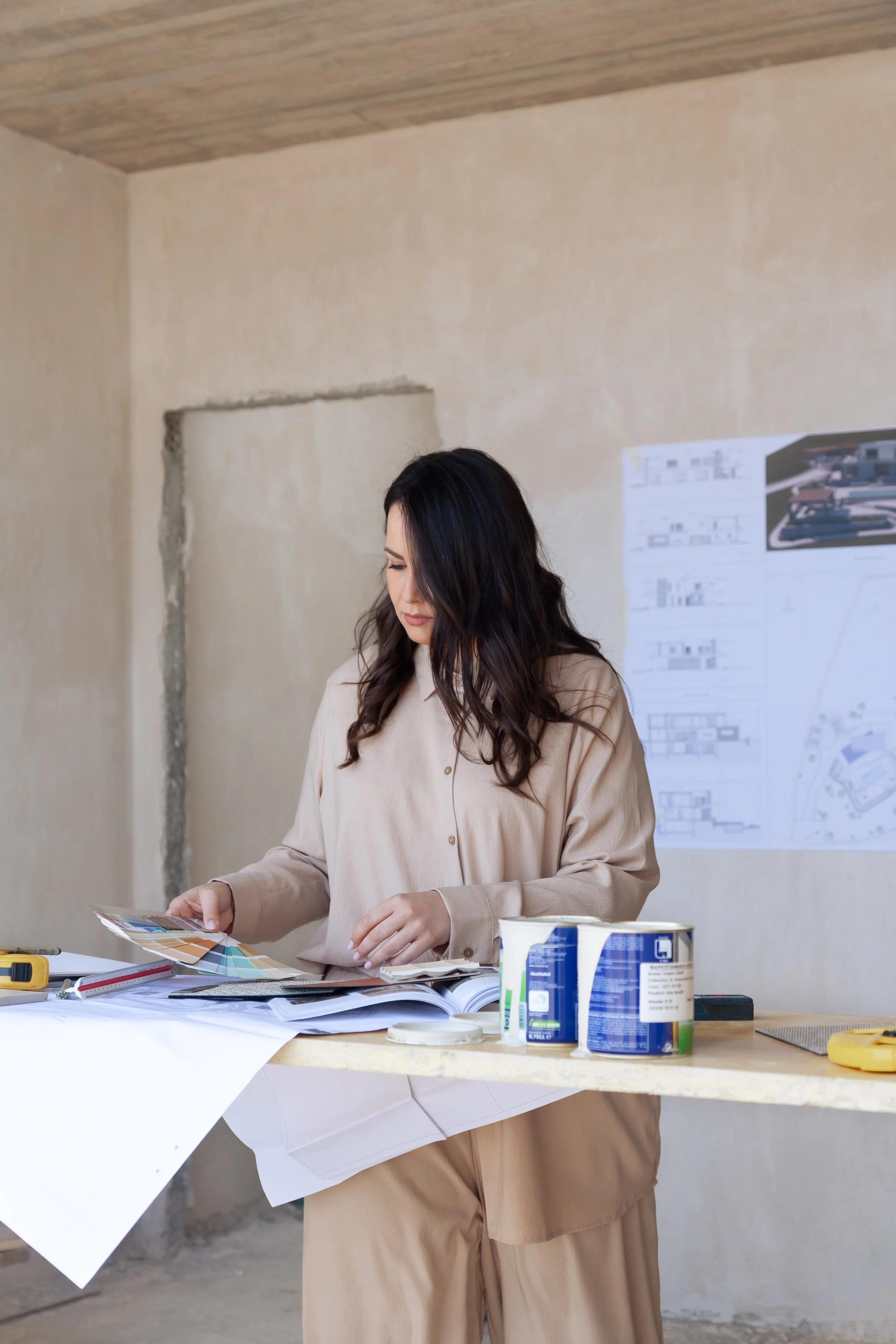Woman reviewing color samples at construction site with blueprints on table.