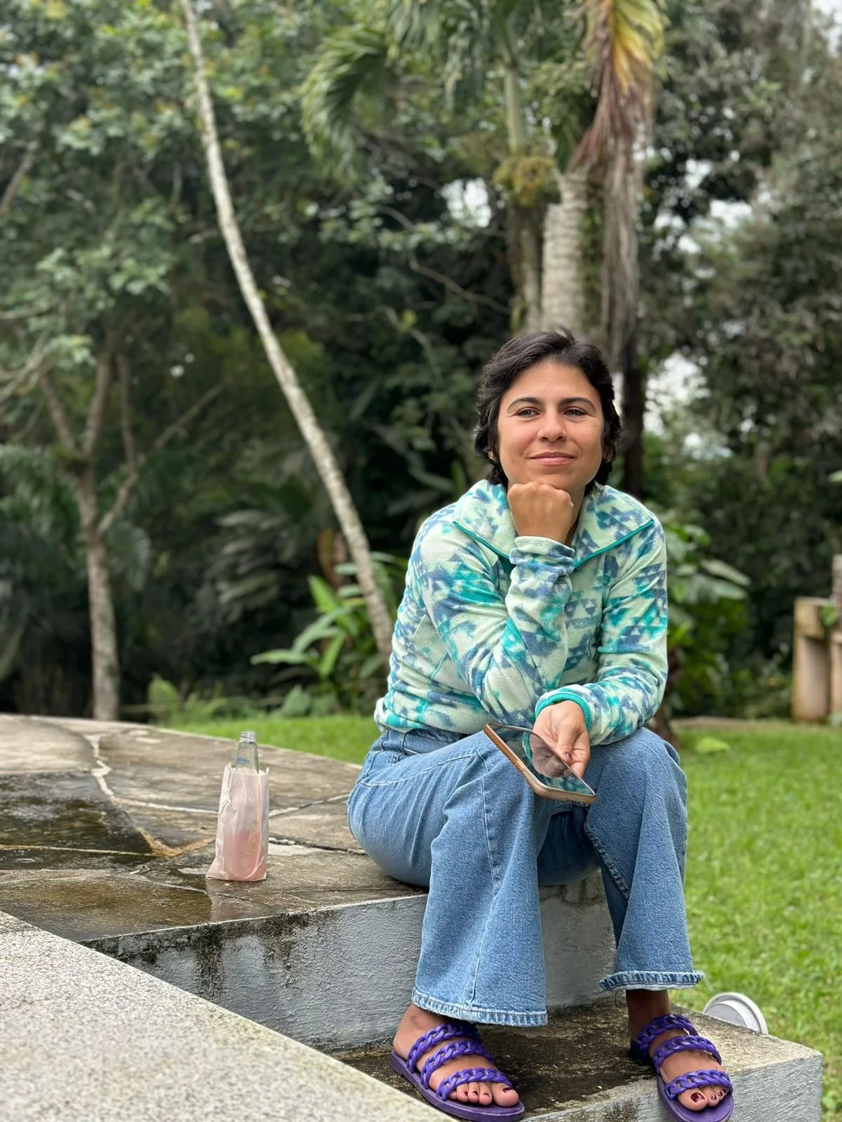 Joven sentada en un lugar exterior compartiendo su historia de fe a Adora y Celebra