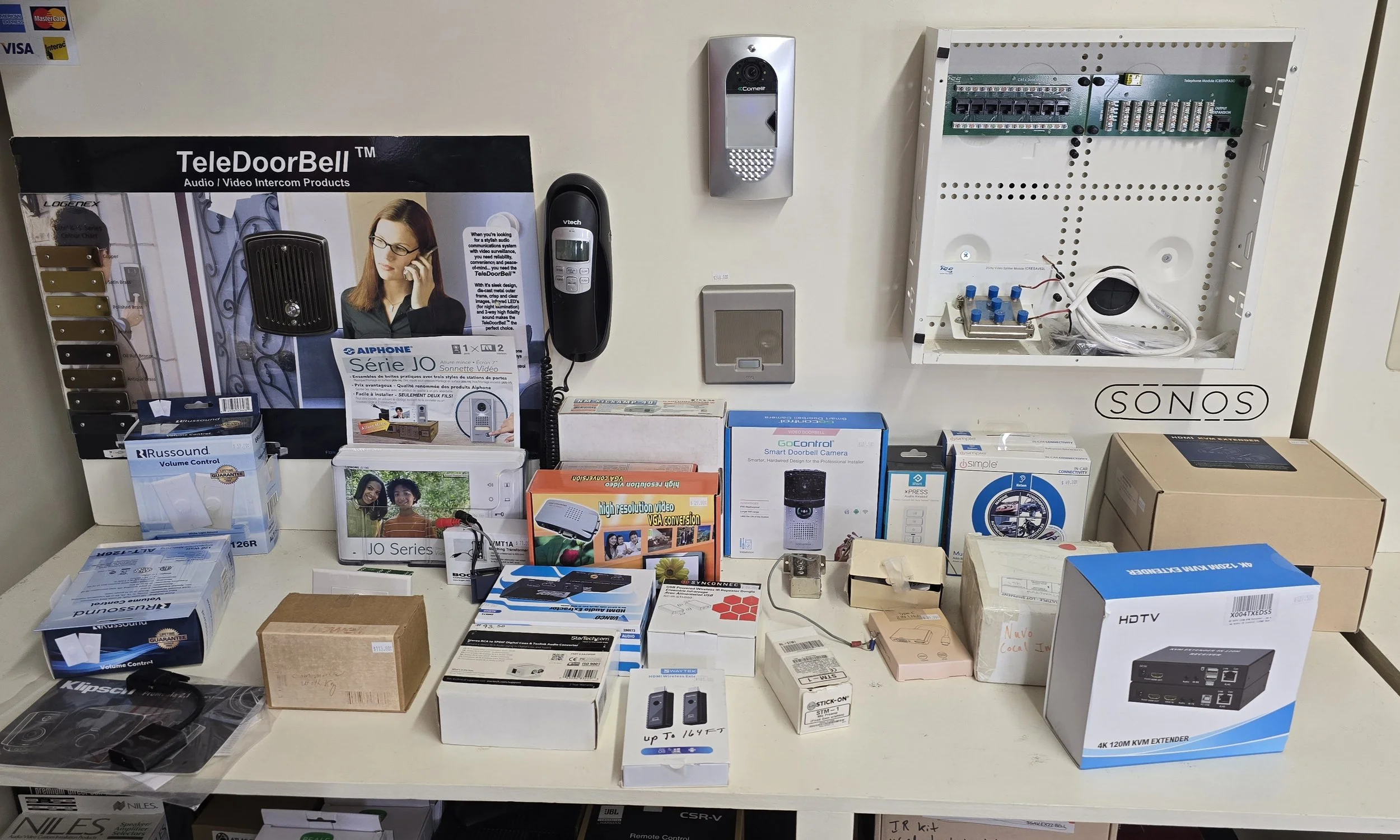 Table with various electronic security and home automation products, including video doorbells, cameras, routers, and control boxes.