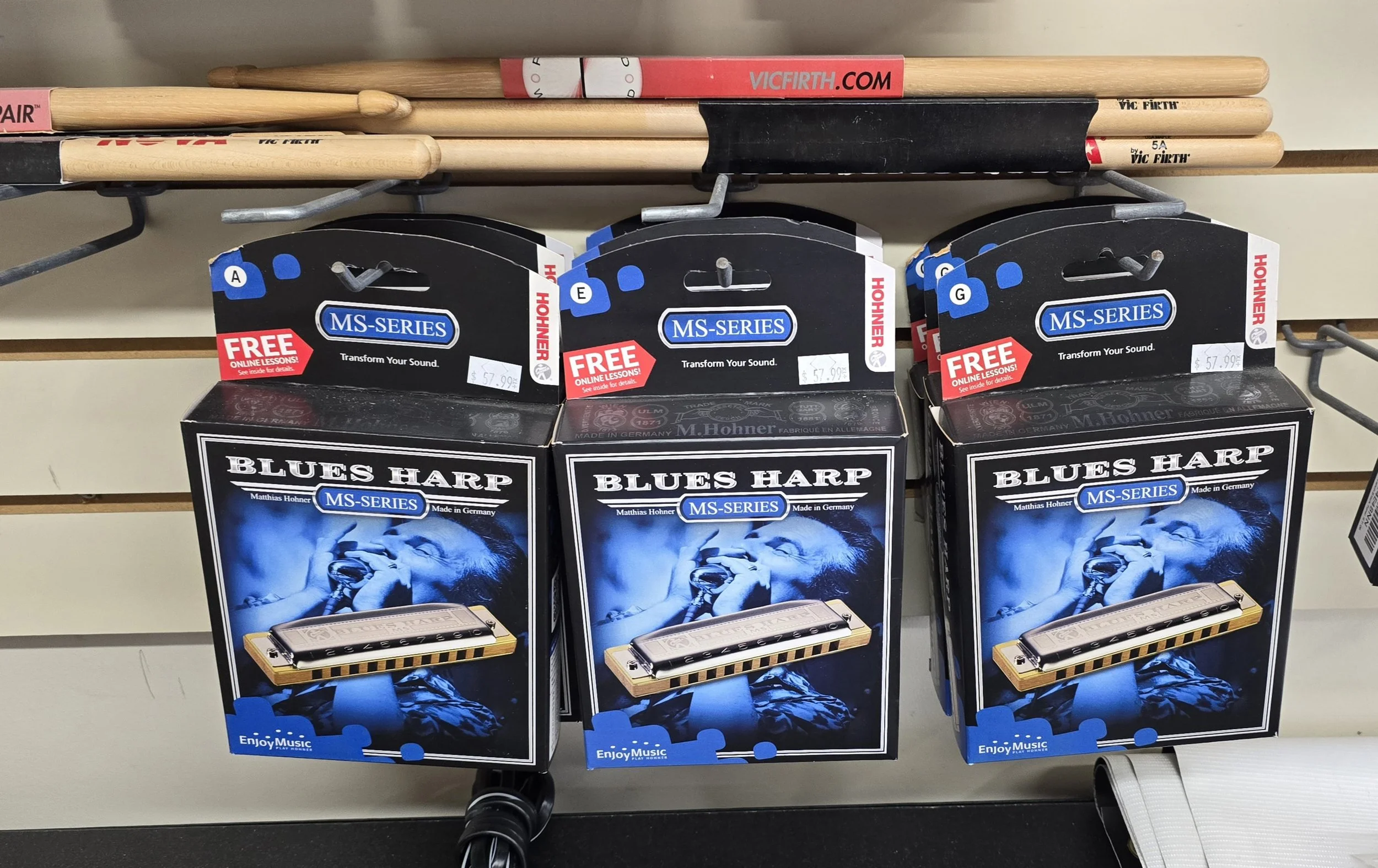 Three boxes of Blues Harp harmonicas in MS-Series, with a blue image of a person singing into a microphone on the packaging, displayed on store shelf.