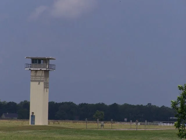 This is a gun tower. A guard watches over his specific sector with an AR-15 assault rifle for anything out of the ordinary or if someone escapes. They are permitted to use lethal force if necessary.