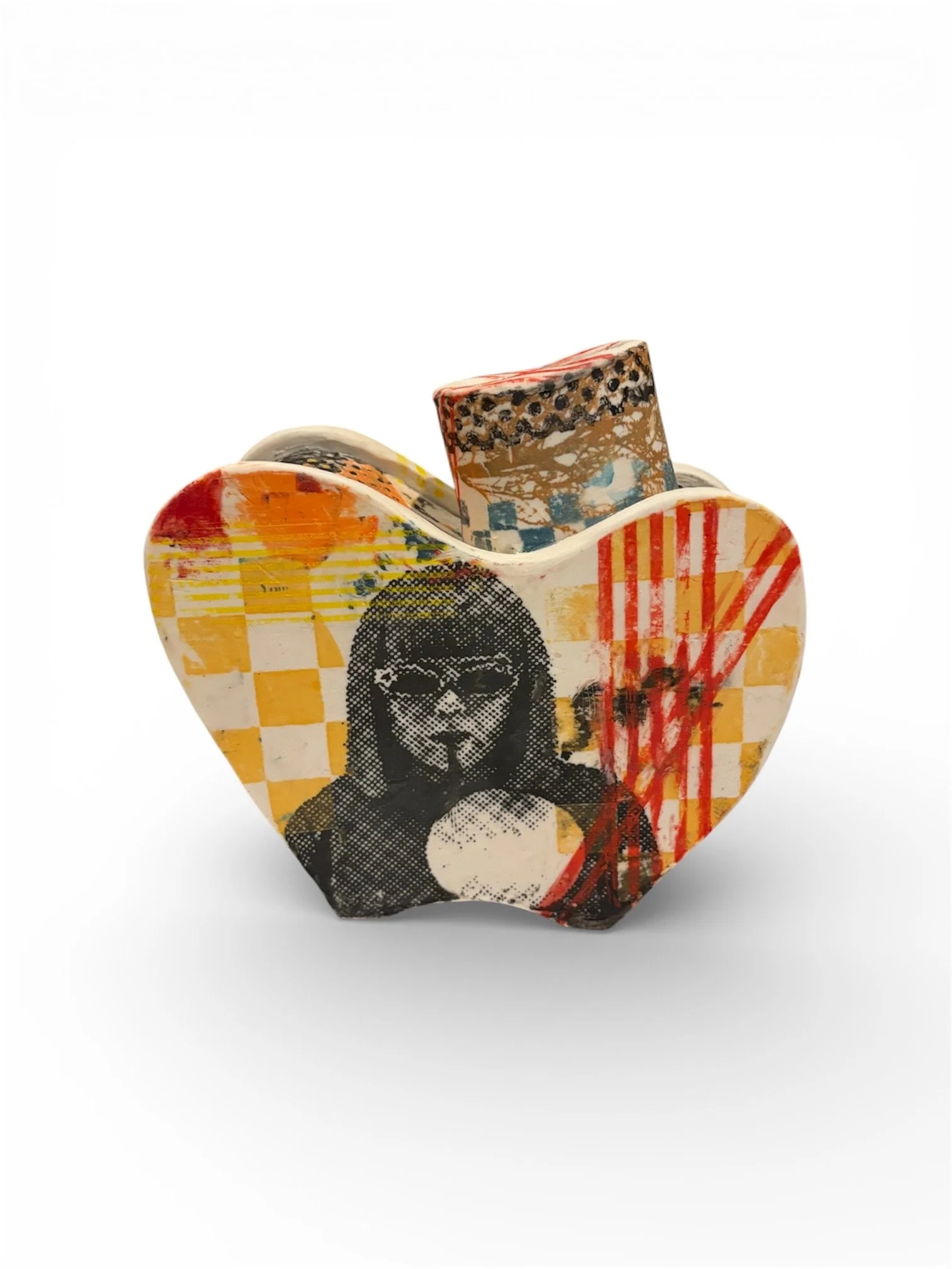 A heart-shaped sculpture with graffiti-style artwork, including a woman with sunglasses and a ball, vibrant red, yellow, and black colors, and abstract patterns.