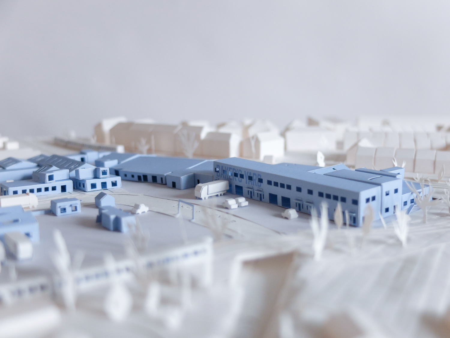 Intricate paper model with blue industrial buildings and white landscaping and details