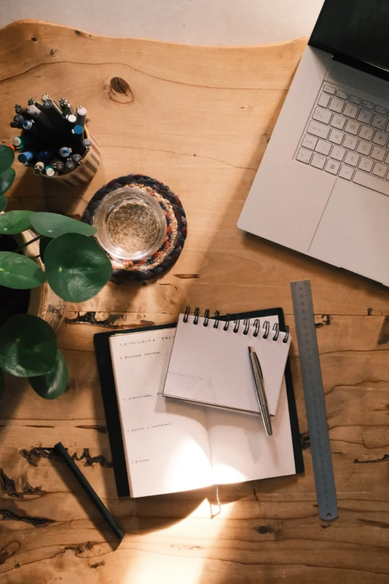 Overhead view of desk set for a meeting with sketchbooks, pens and laptop