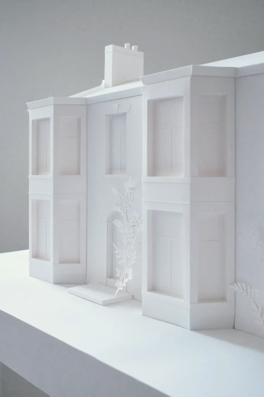 White paper model of a victorian villa with grand bay windows and arched front door