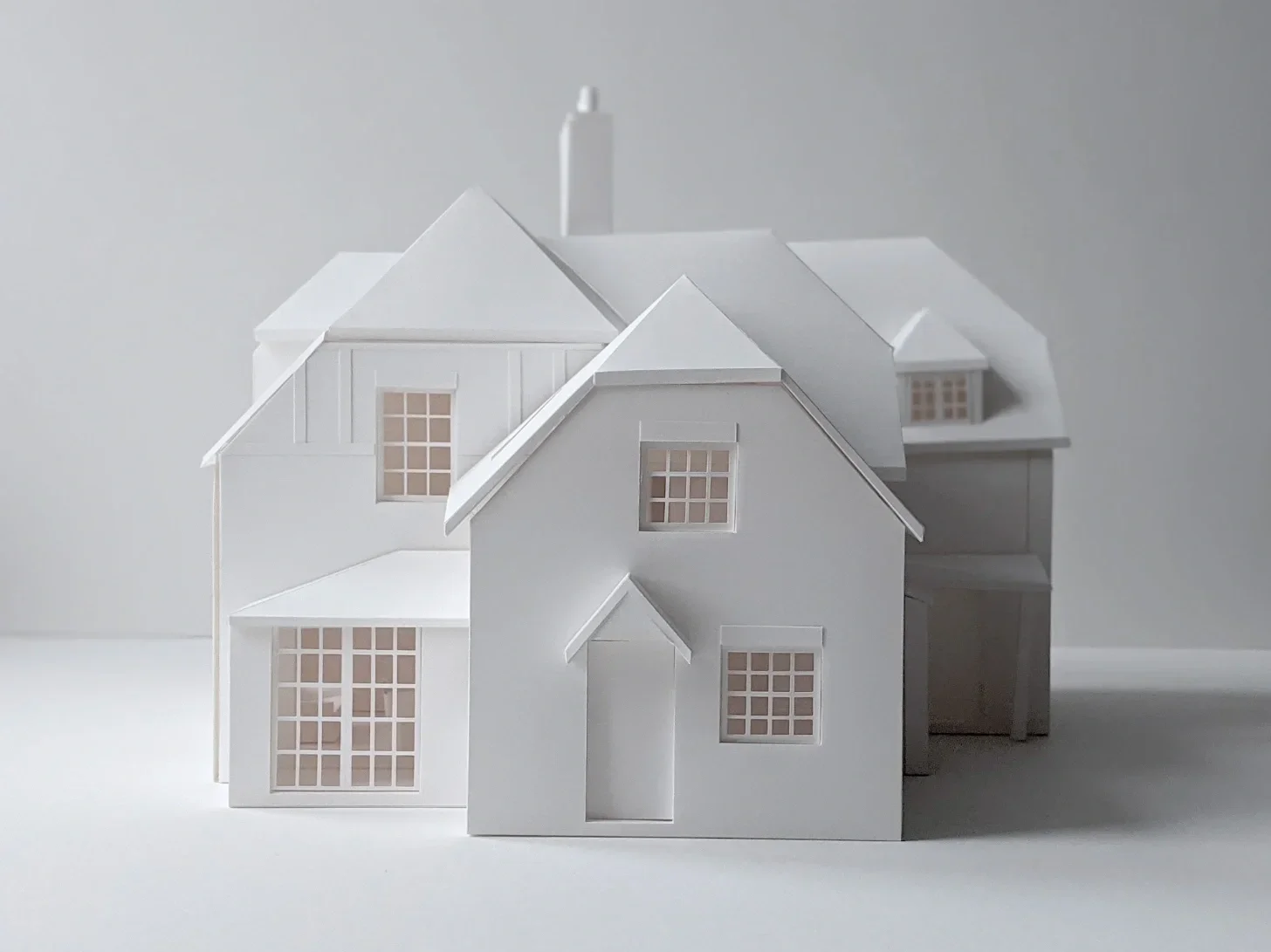 White paper model of a historic house with hipped roofs and mullioned windows