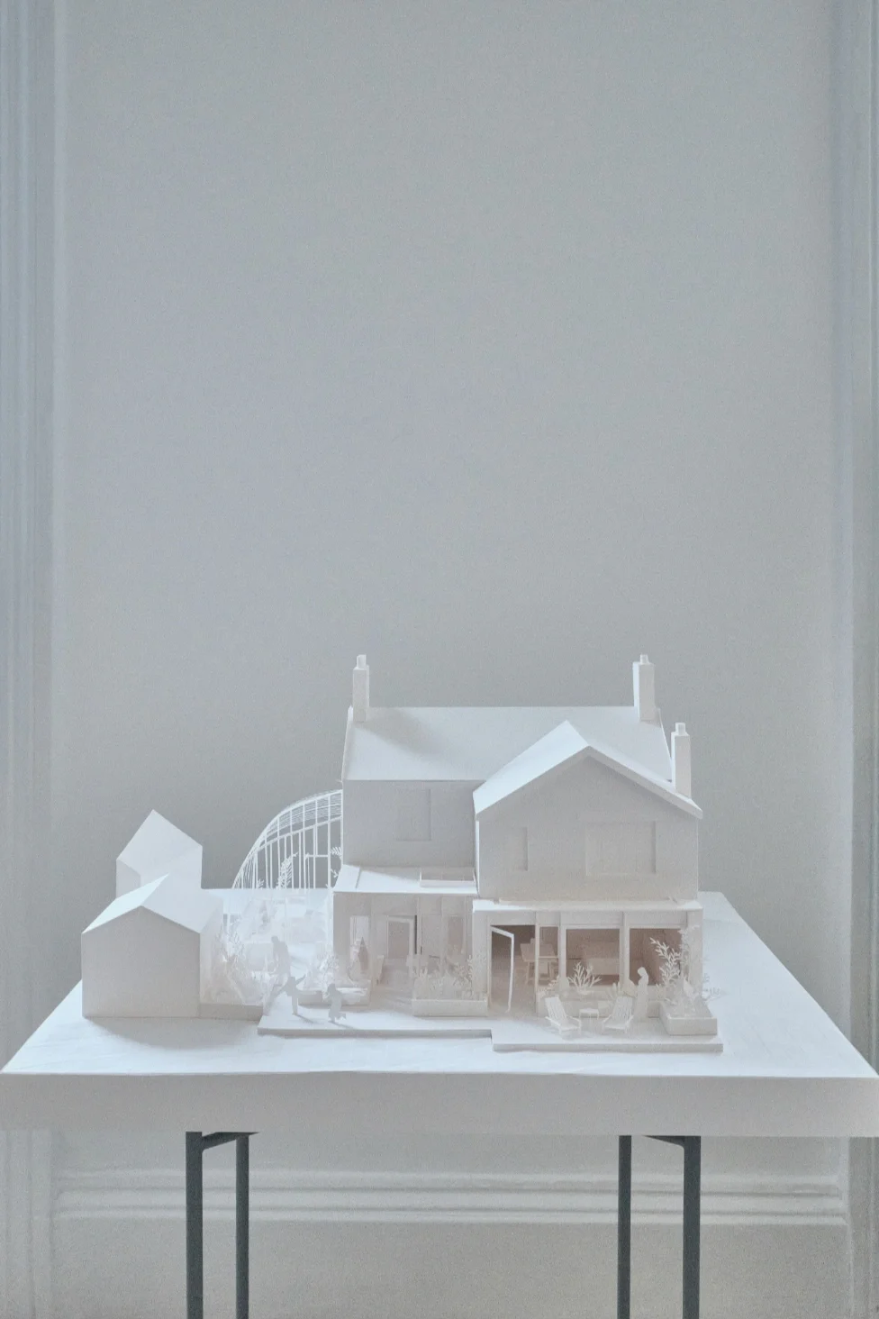 White paper model of a traditional house with a contemporary extension and outdoor terrace